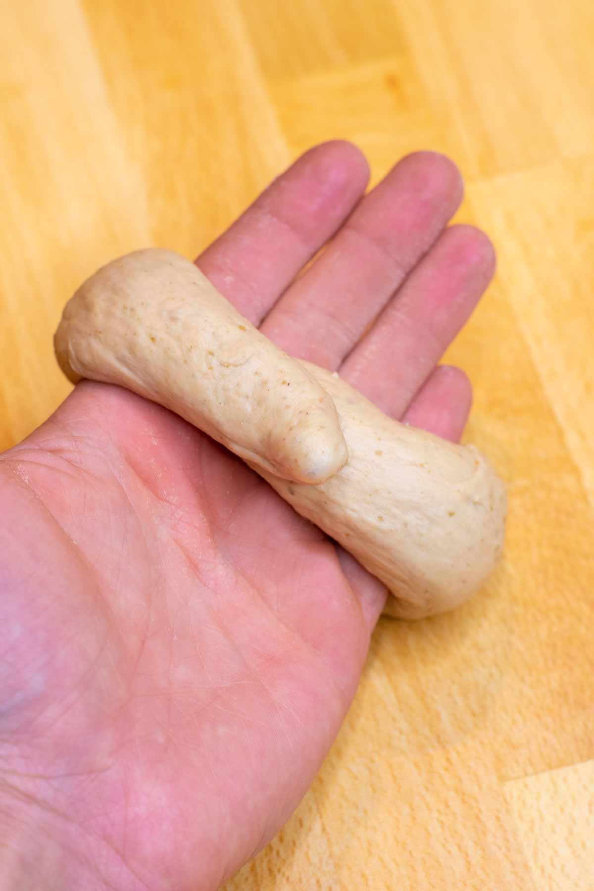 Rope of bagel dough wrapped around palm of hand
