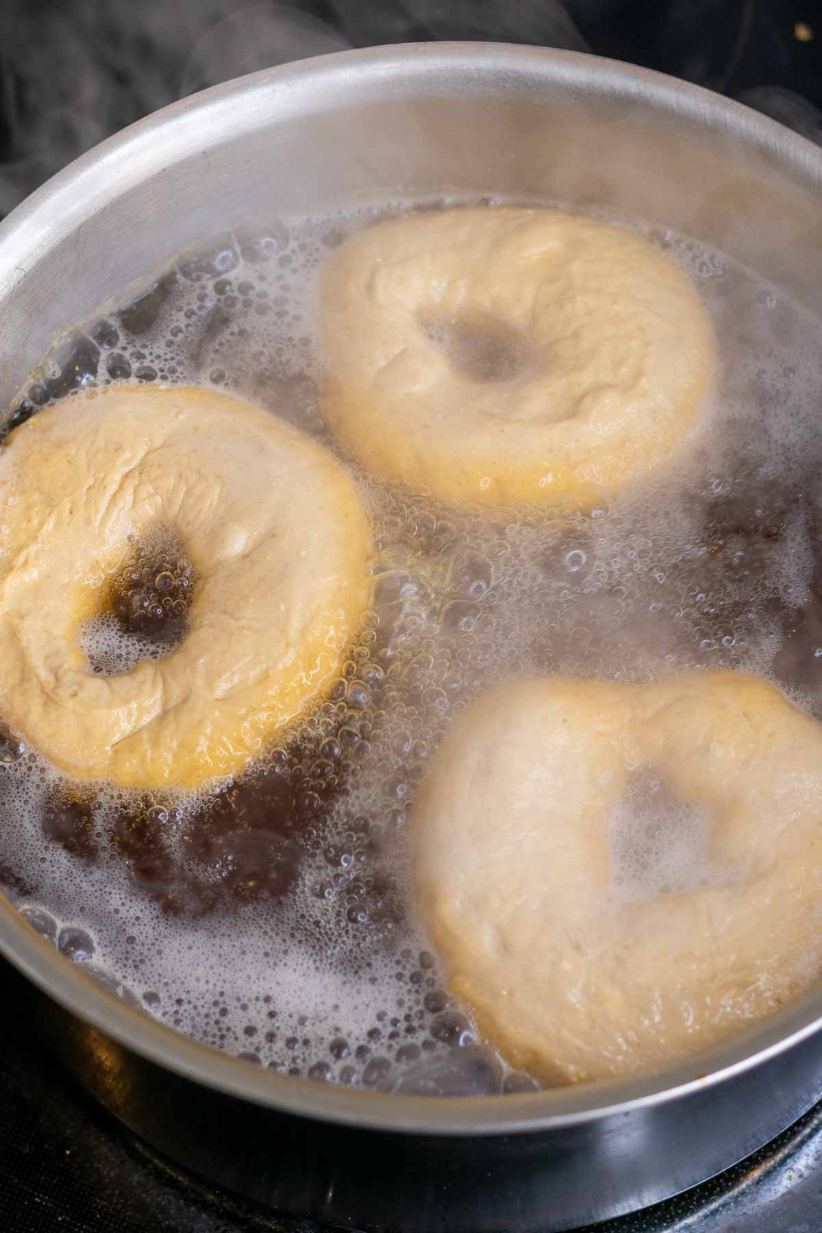 Bagels boiling in pot of water
