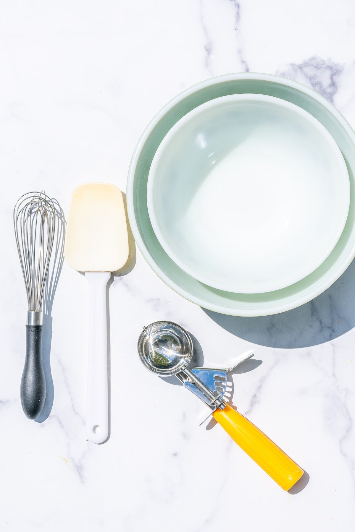 Tools needed for Sourdough discard chocolate chip cookies including mixing bowls, a spatula, whisk, and a cookie scoop.