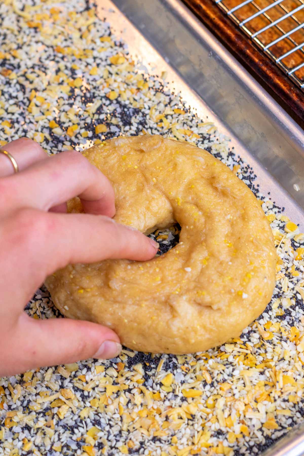 Dipping a side of the bagel onto everything bagel seasoning