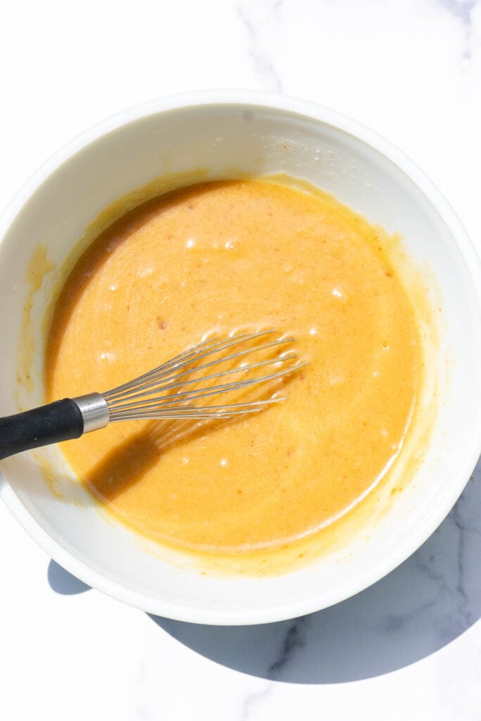 Whisked wet ingredients in bowl with a whisk