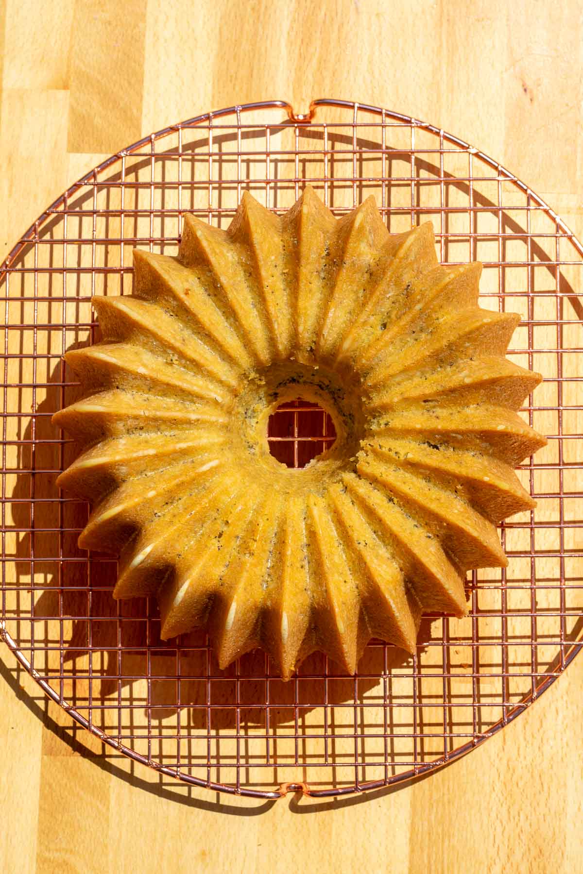 Sourdough lemon poppy seed bundt cake turned out and cooling on a copper wire rack