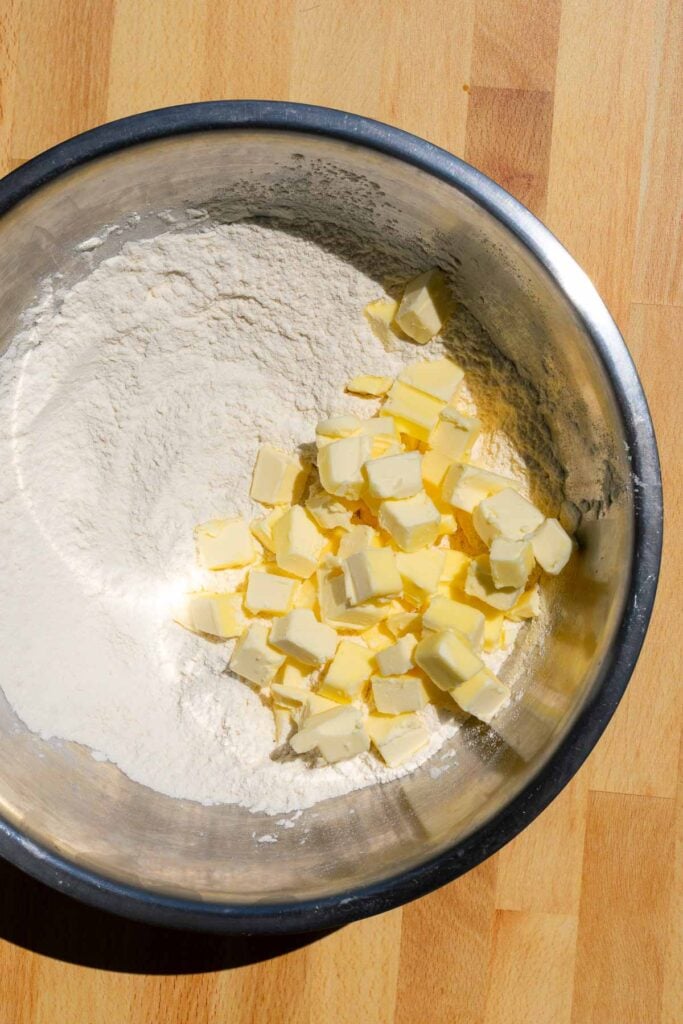 Cubes of butter in mixing bowl with flour