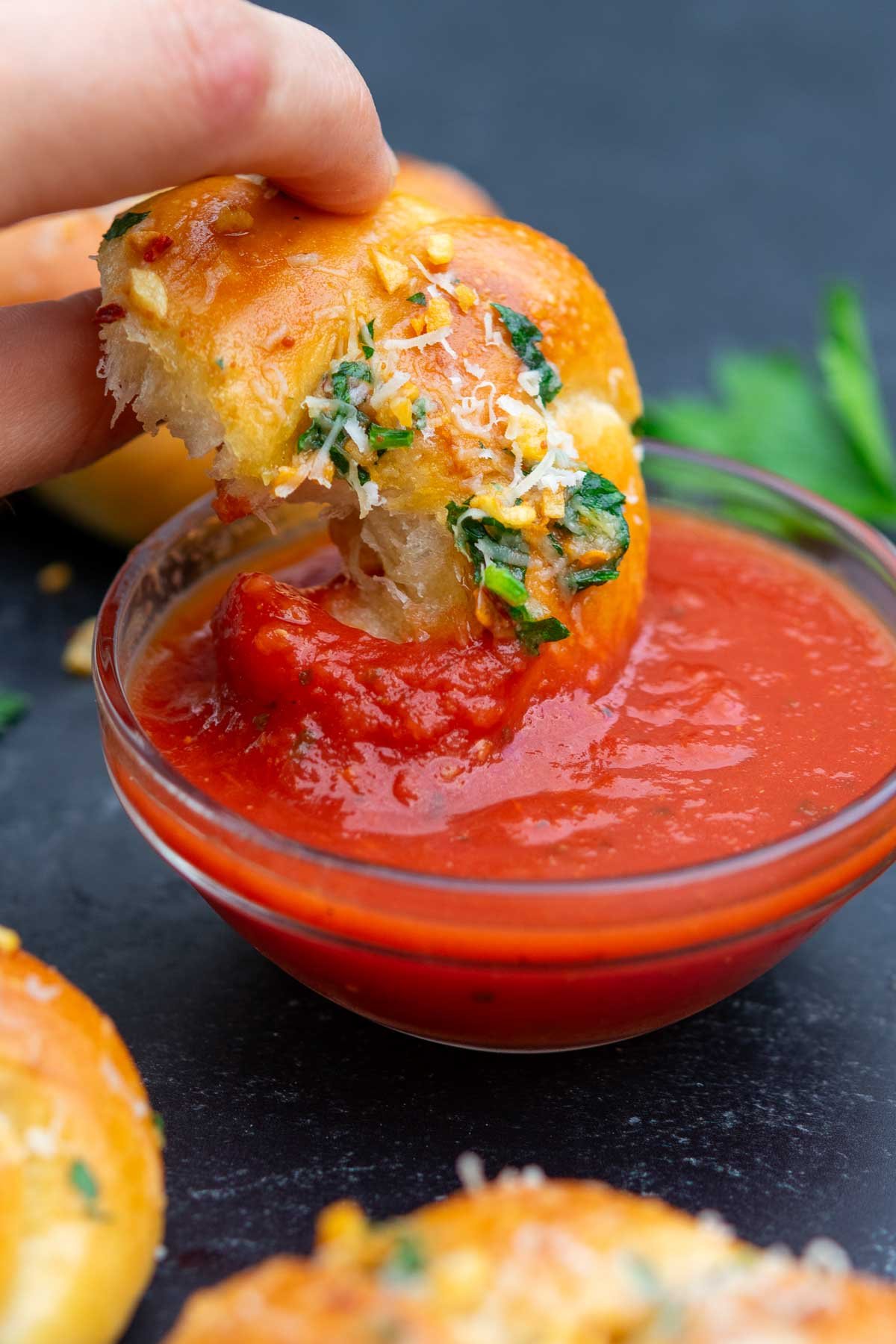 Dipping a sourdough garlic knot into a bowl of marinara sauce