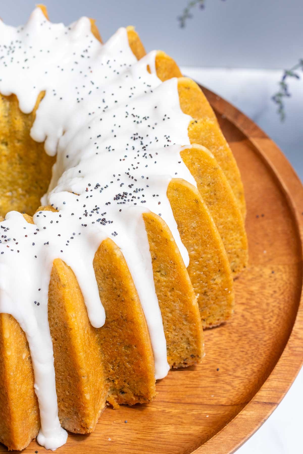 Lemon glaze dripping down sides of sourdough lemon poppy seed bundt cake