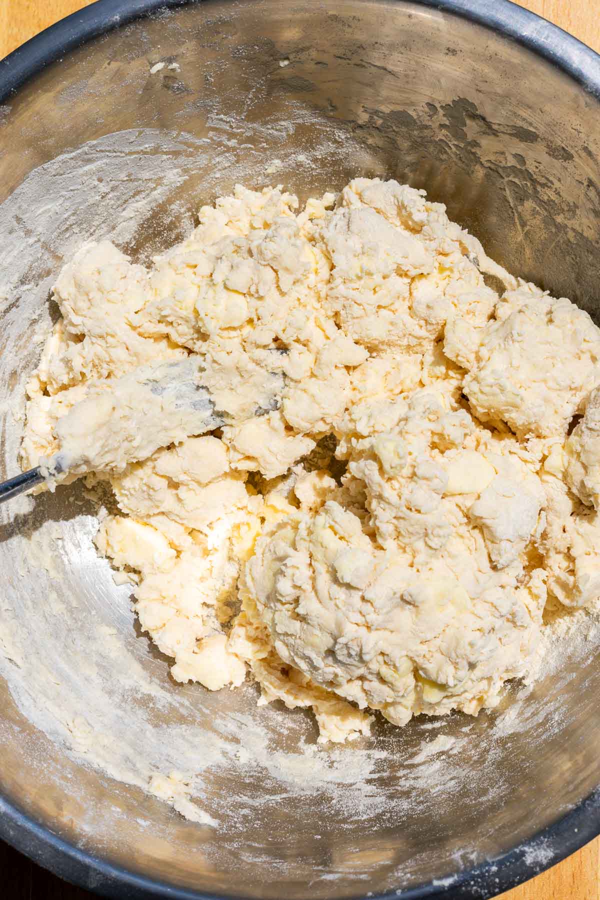 Clumps of mixing sourdough rough puff pastry dough in a mixing bowl