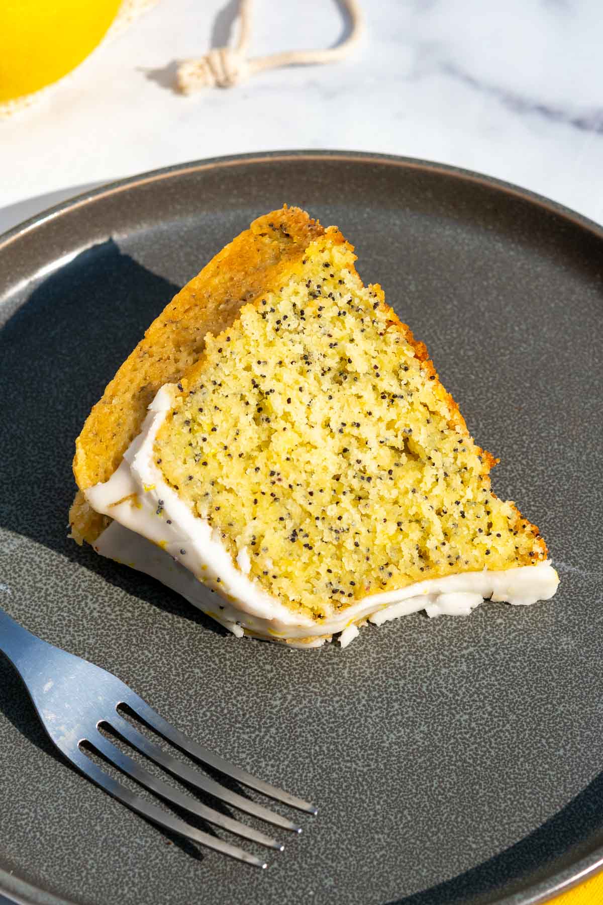 Slice of sourdough lemon poppy seed bundt cake with icing on a plate