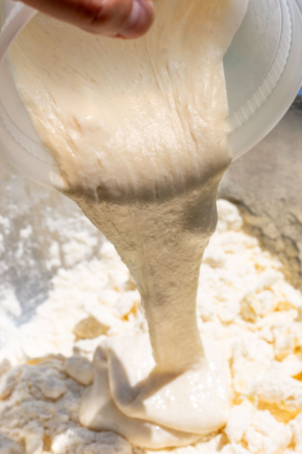 Pouring sourdough discard into mixing bowl of four, salt, and butter