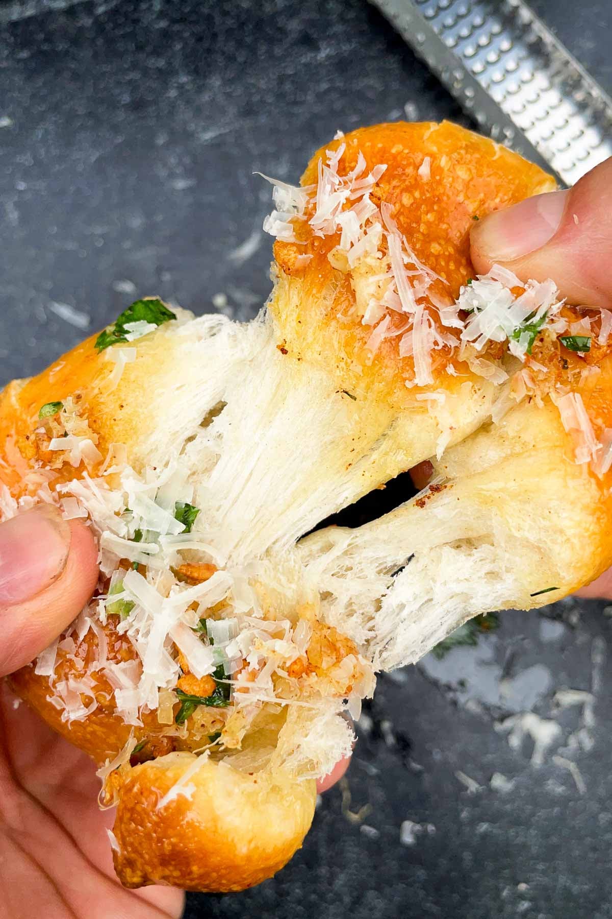 Hands pulling apart a sourdough garlic knot
