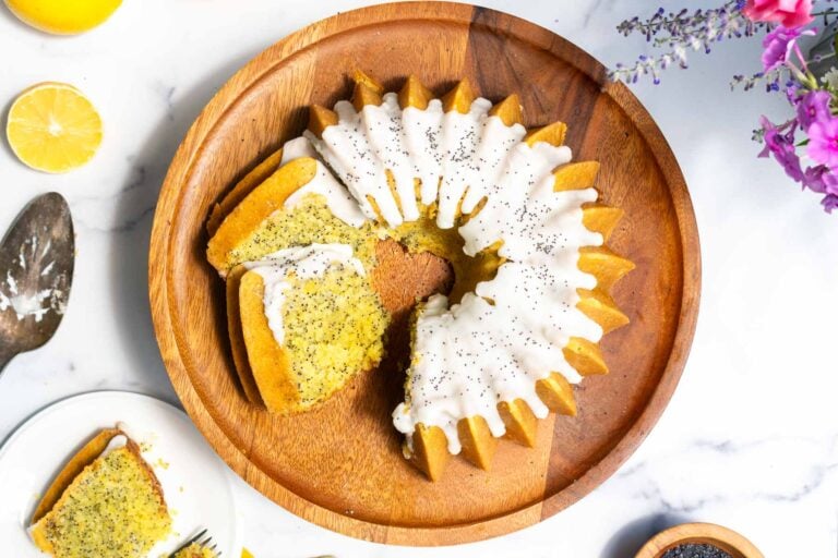 Sourdough Lemon Poppyseed Bundt Cake on a cake stand with slices cut and a lemon glaze