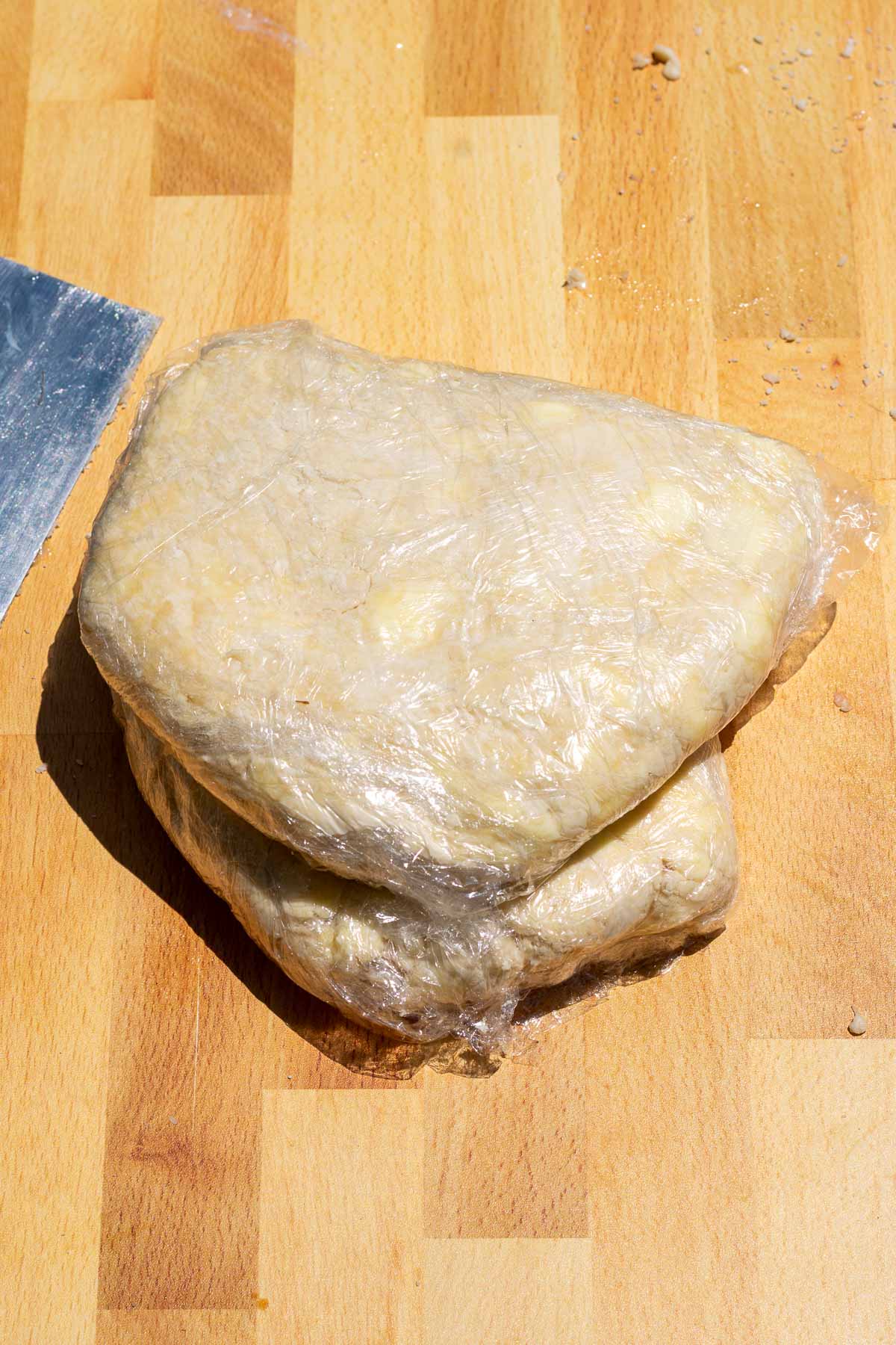 Two discs of sourdough rough puff pastry wrapped in plastic wrap