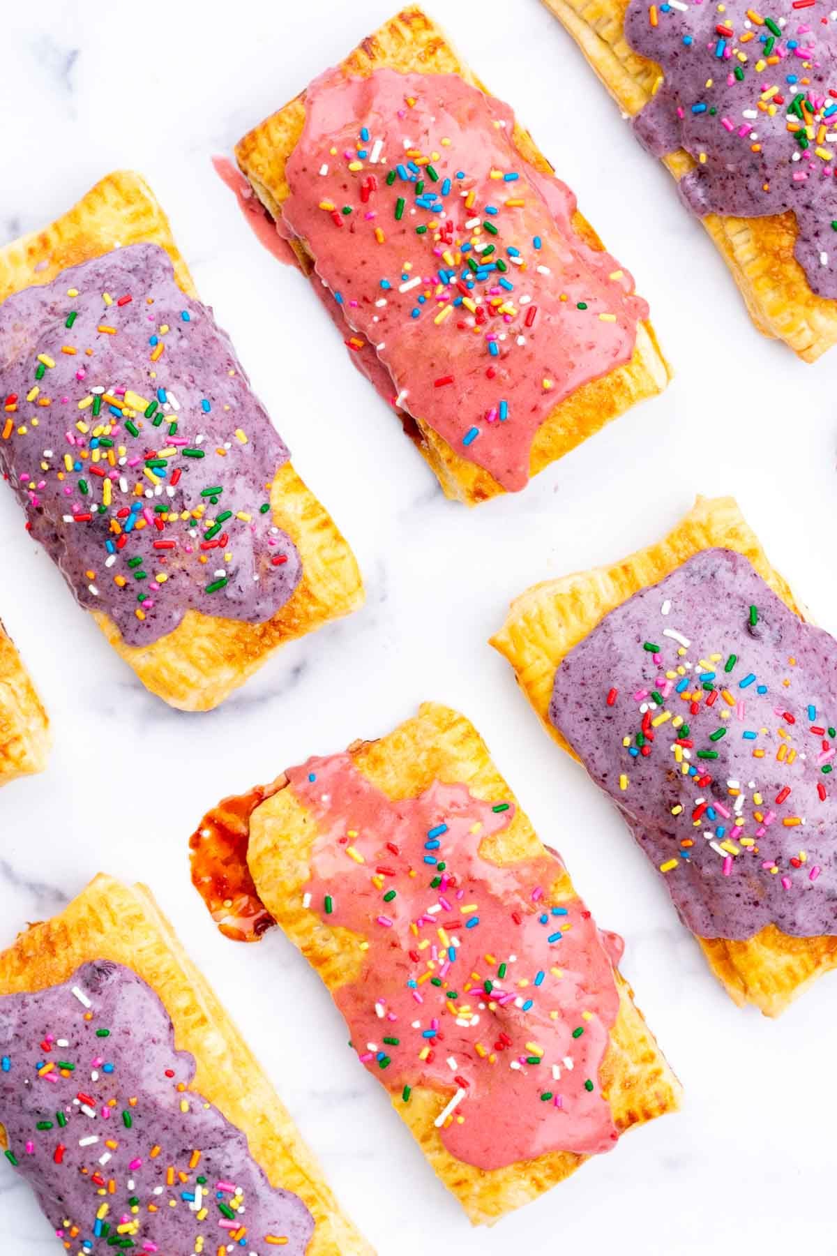 Sourdough pop tarts on a marble surface with strawberry and blueberry icings