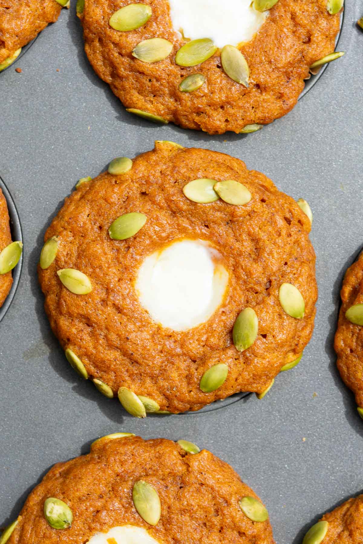 A baked sourdough pumpkin cream cheese muffin in a muffin pan