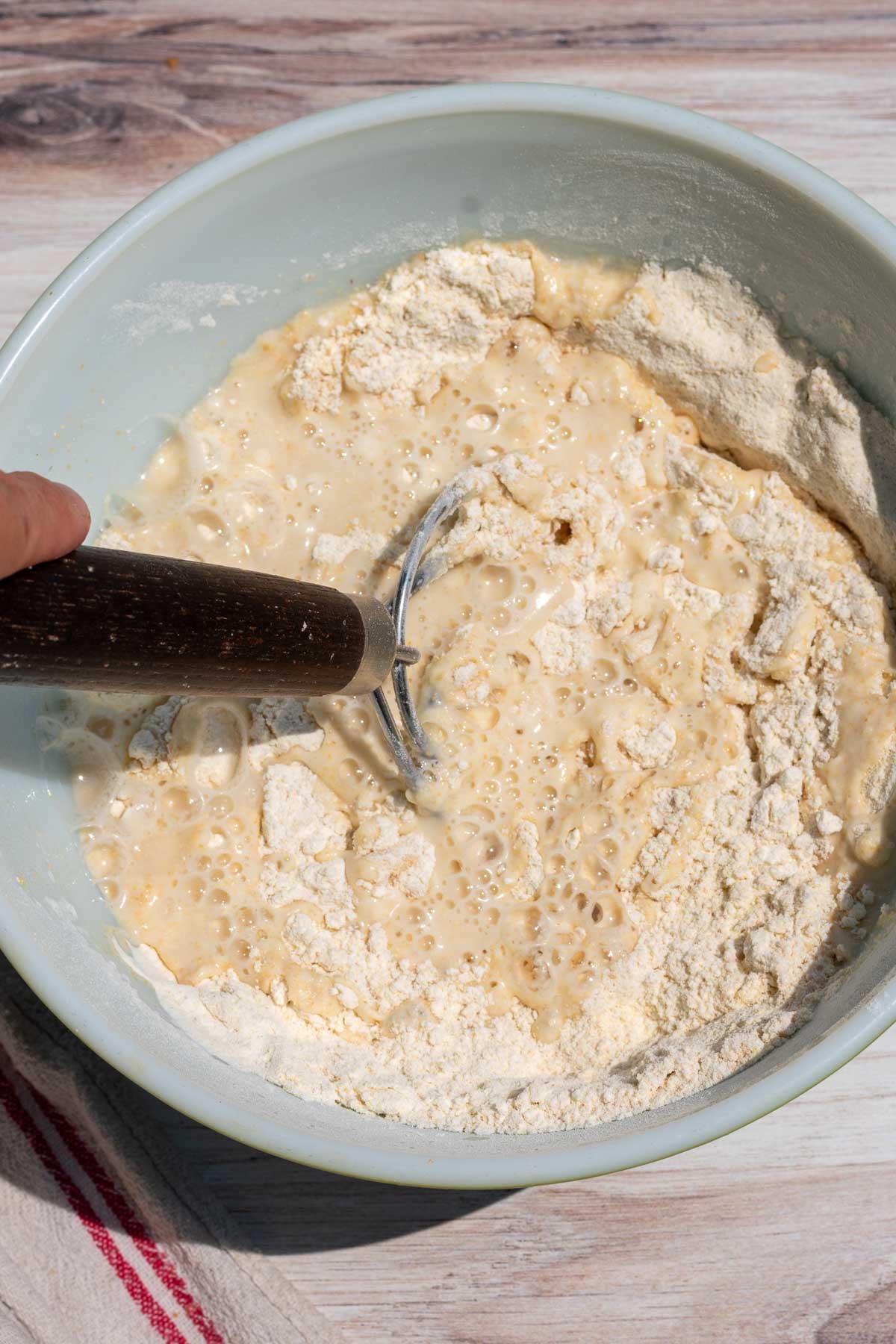Mixing einkorn flour, bread flour, and water with Danish dough whisk in a bowl.