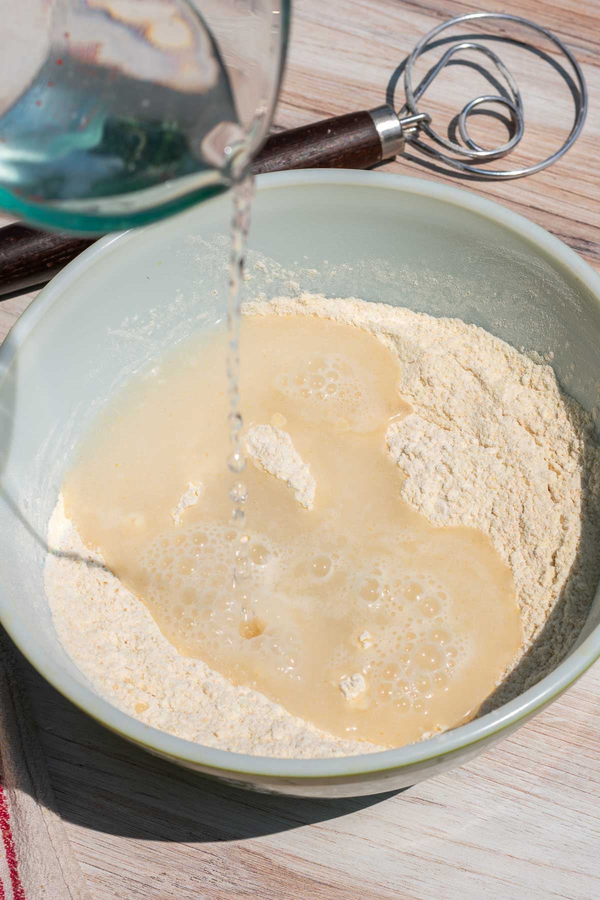 Pouring water into bowl of bread and einkorn flour