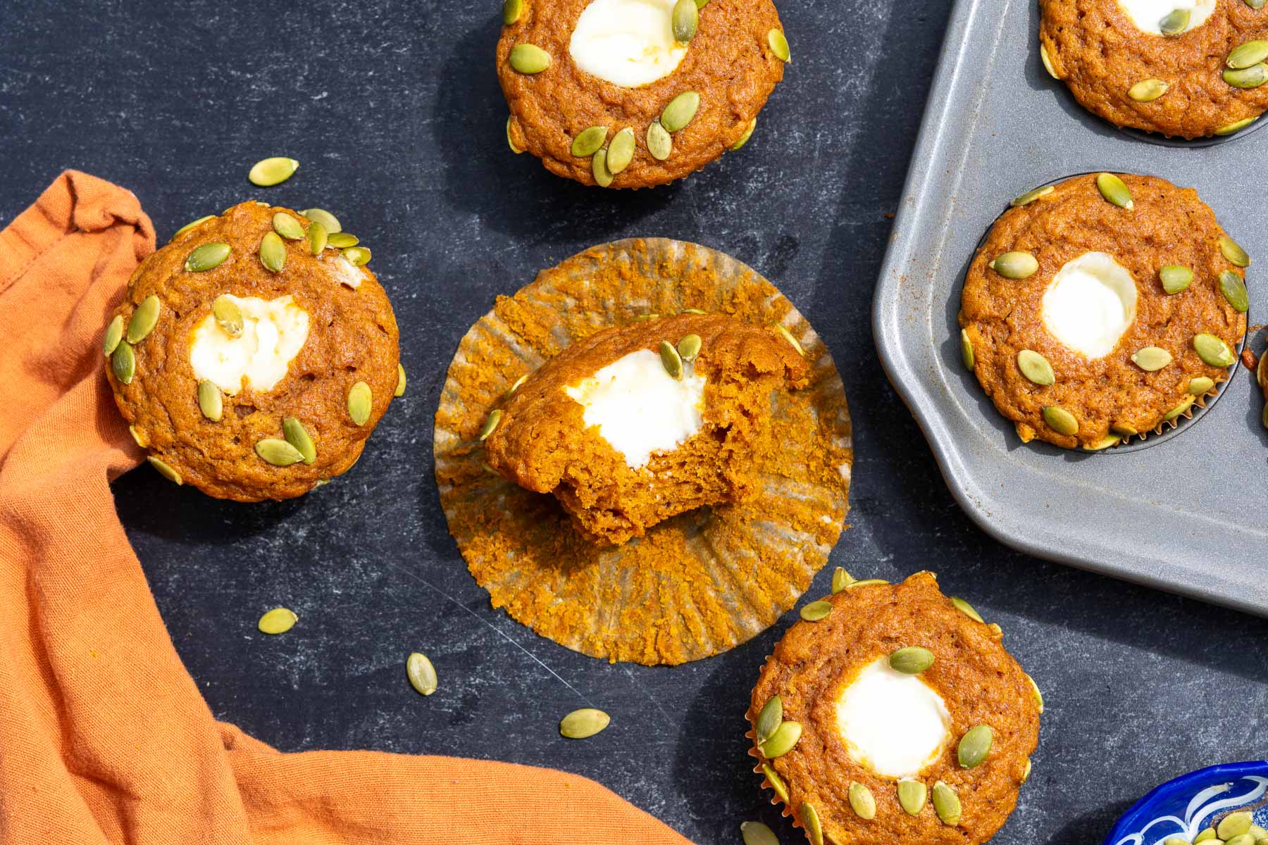 Sourdough pumpkin cream cheese muffins with one in the middle with a bite taken out of it.