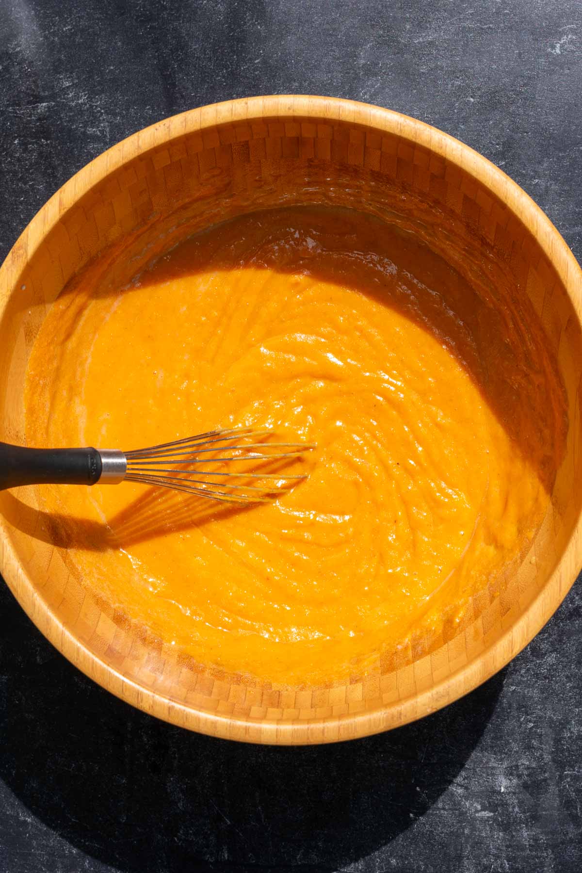 Whisked wet ingredients for sourdough pumpkin muffins in bowl with whisk