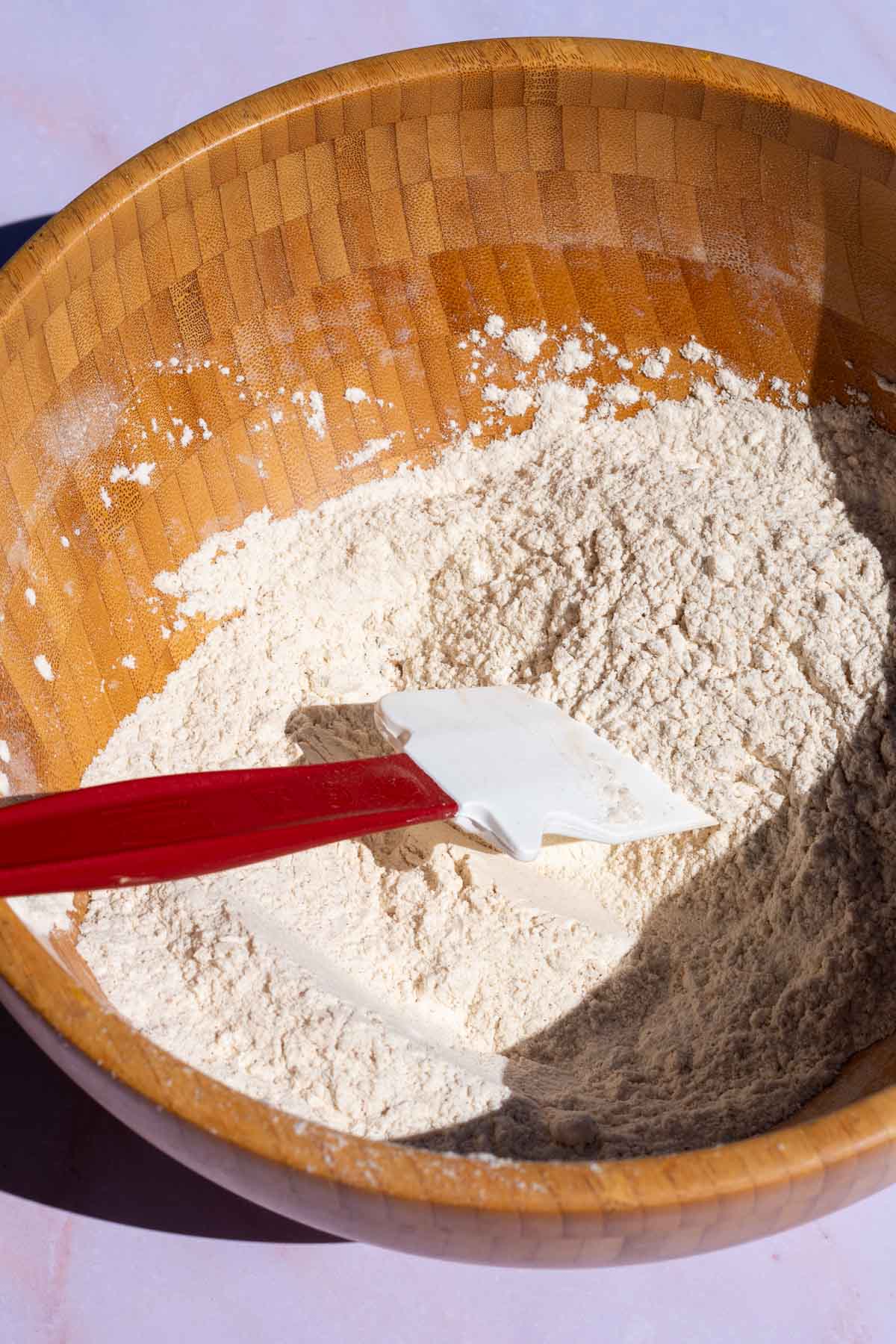 Wooden bowl with sourdough pumpkin scones dry ingredients mixed with a spatula
