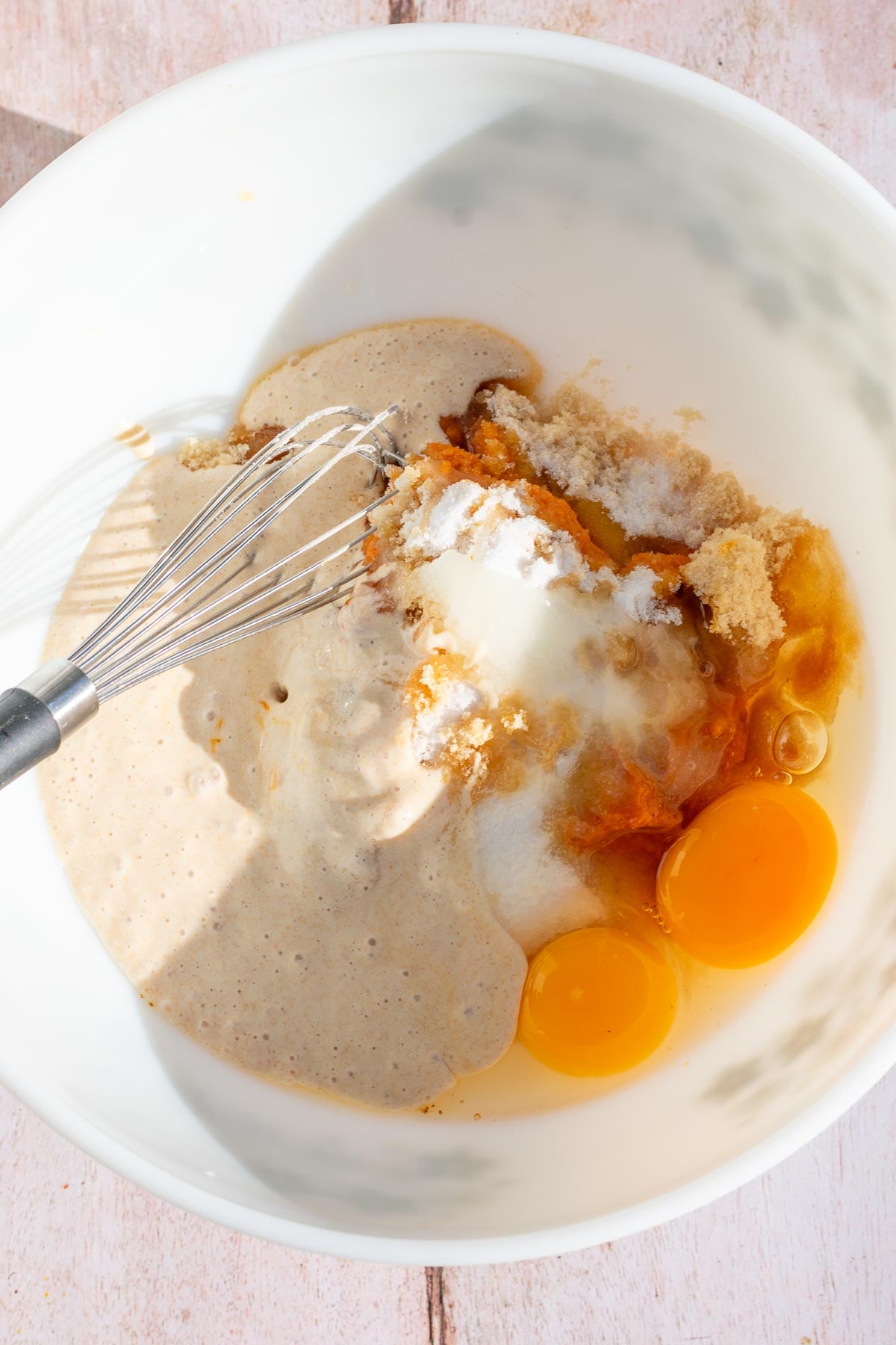 Bowl of unmixed wet ingredients with a whisk.