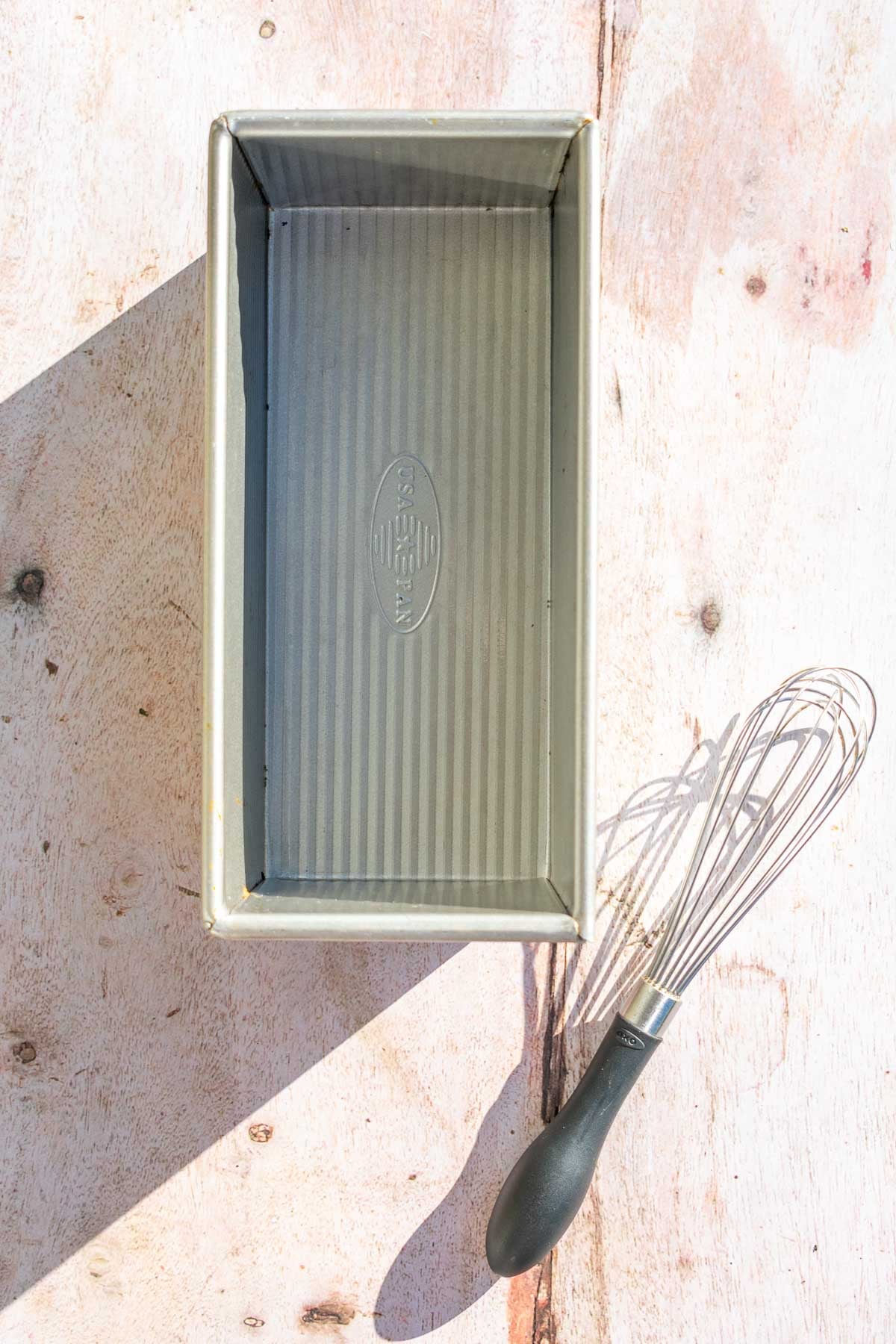 A bread loaf pan and a whisk.