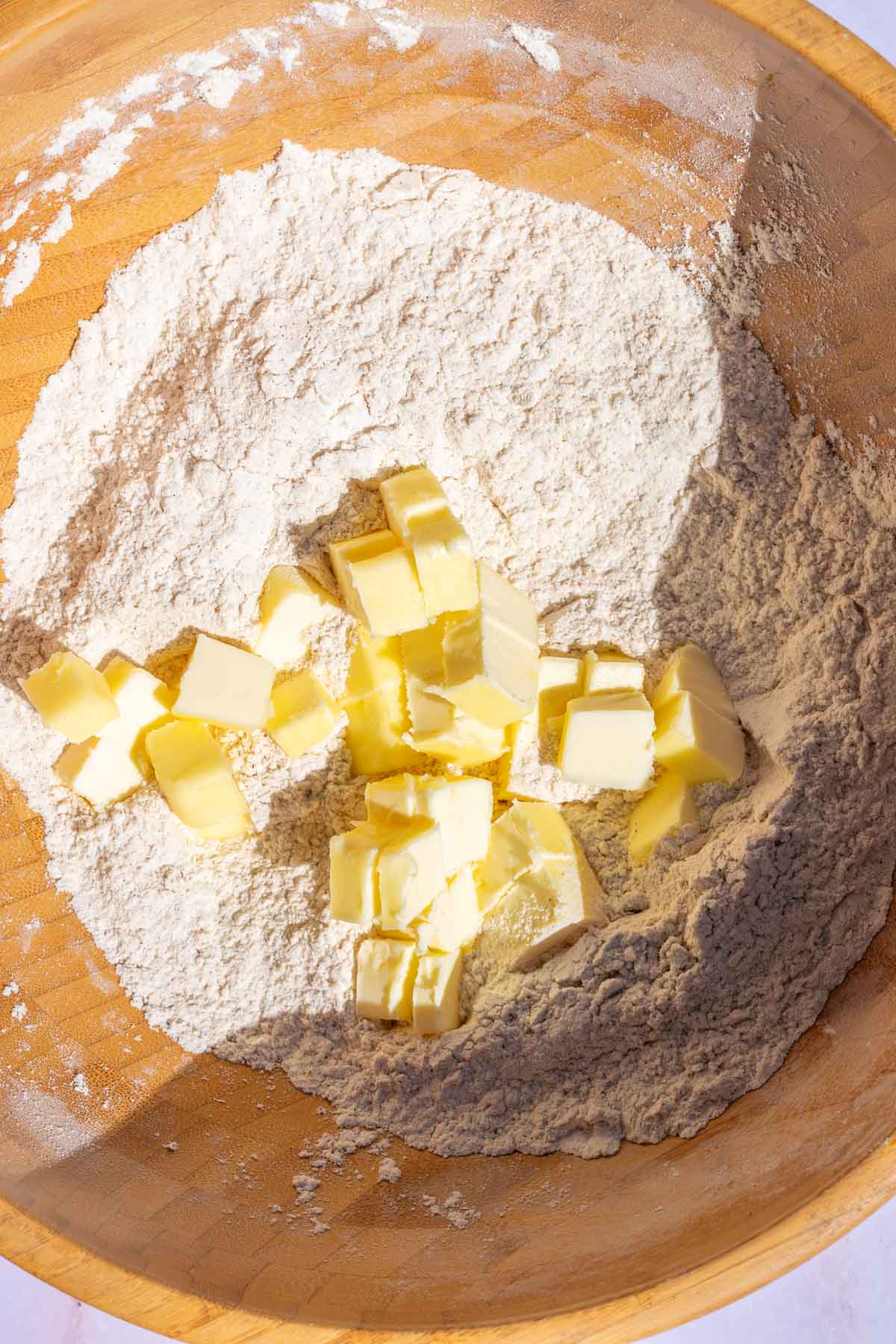 Cubes of butter in bowl of dry ingredients for pumpkin scones.