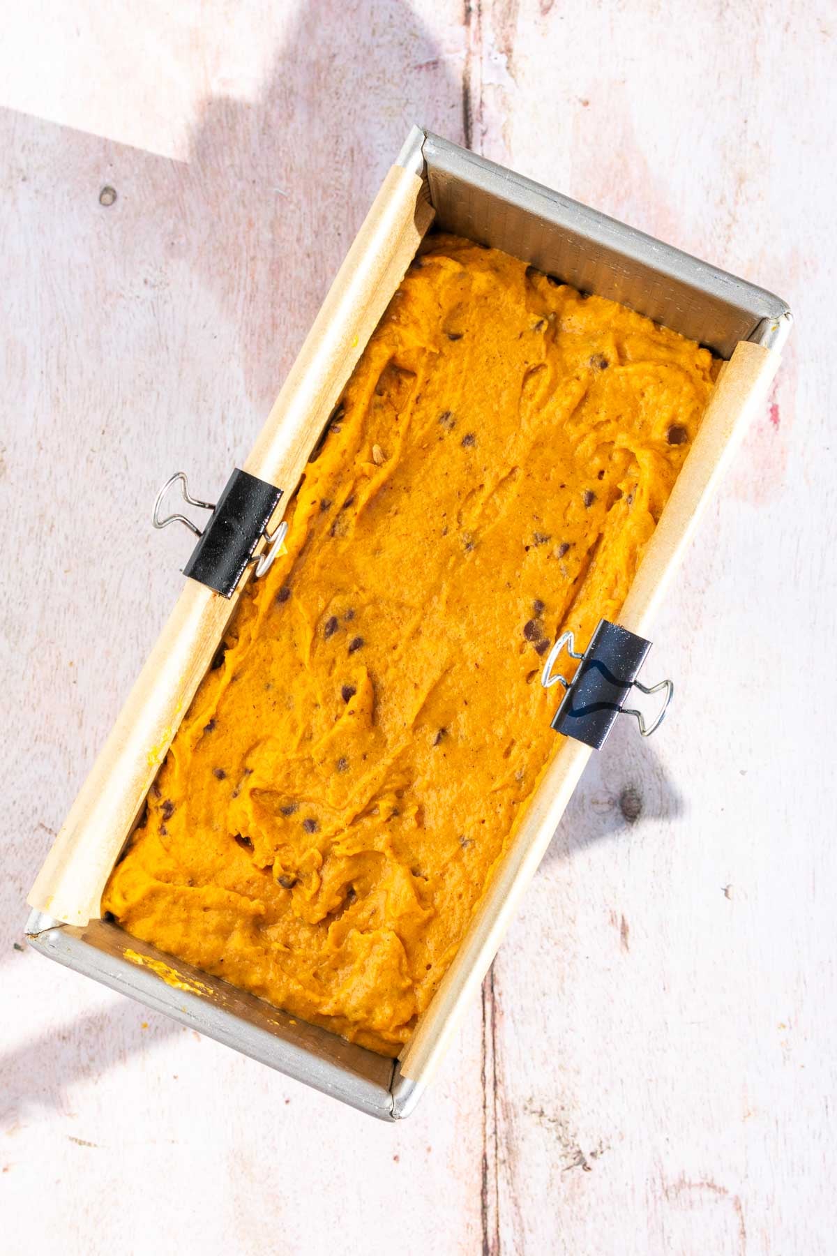 Bread loaf pan with sourdough pumpkin chocolate chip batter unbaked.