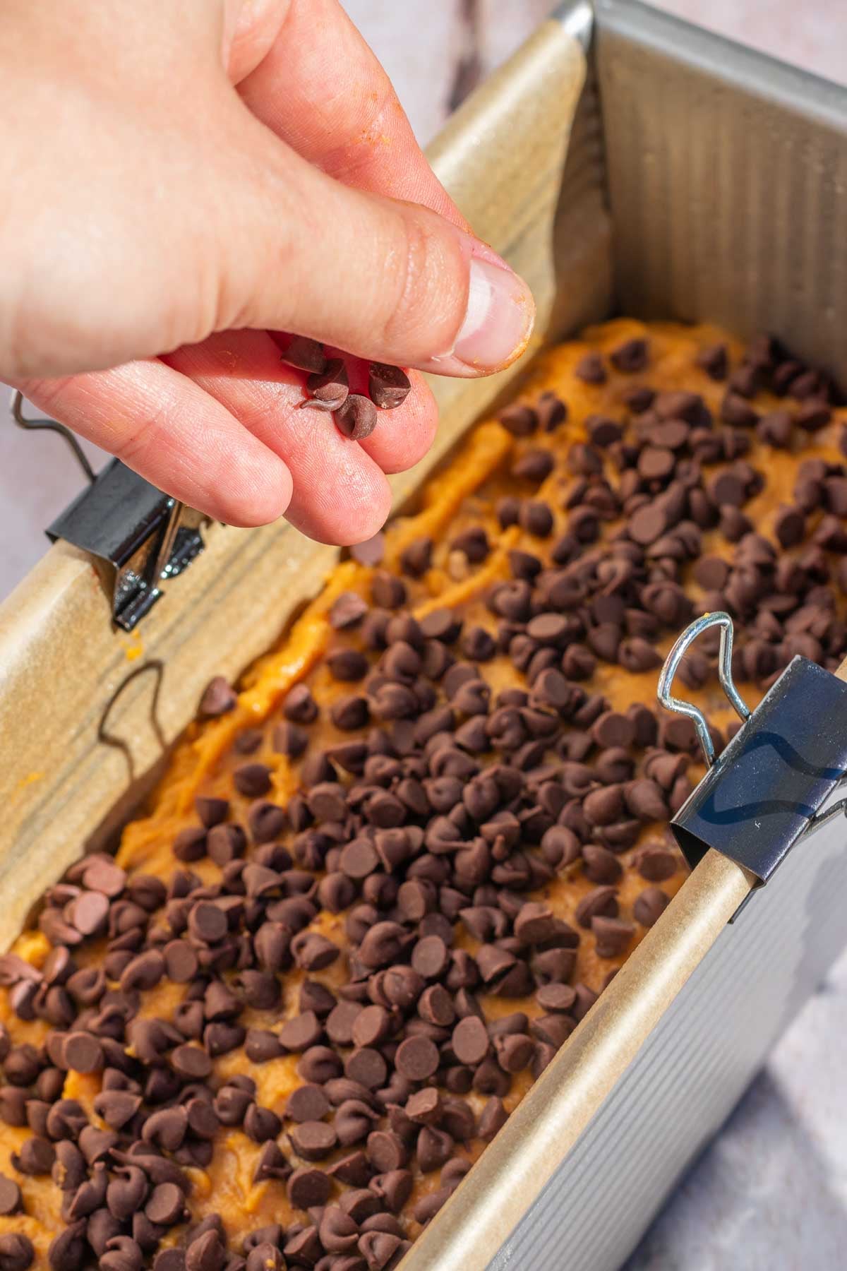 Sprinkling chocolate chips on top of unbaked sourdough pumpkin bread
