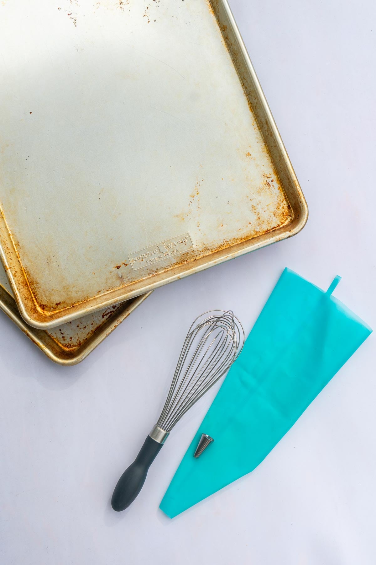 Tools needed for Sourdough pumpkin whoopie pies including sheet pans, a whisk, and a piping bag.