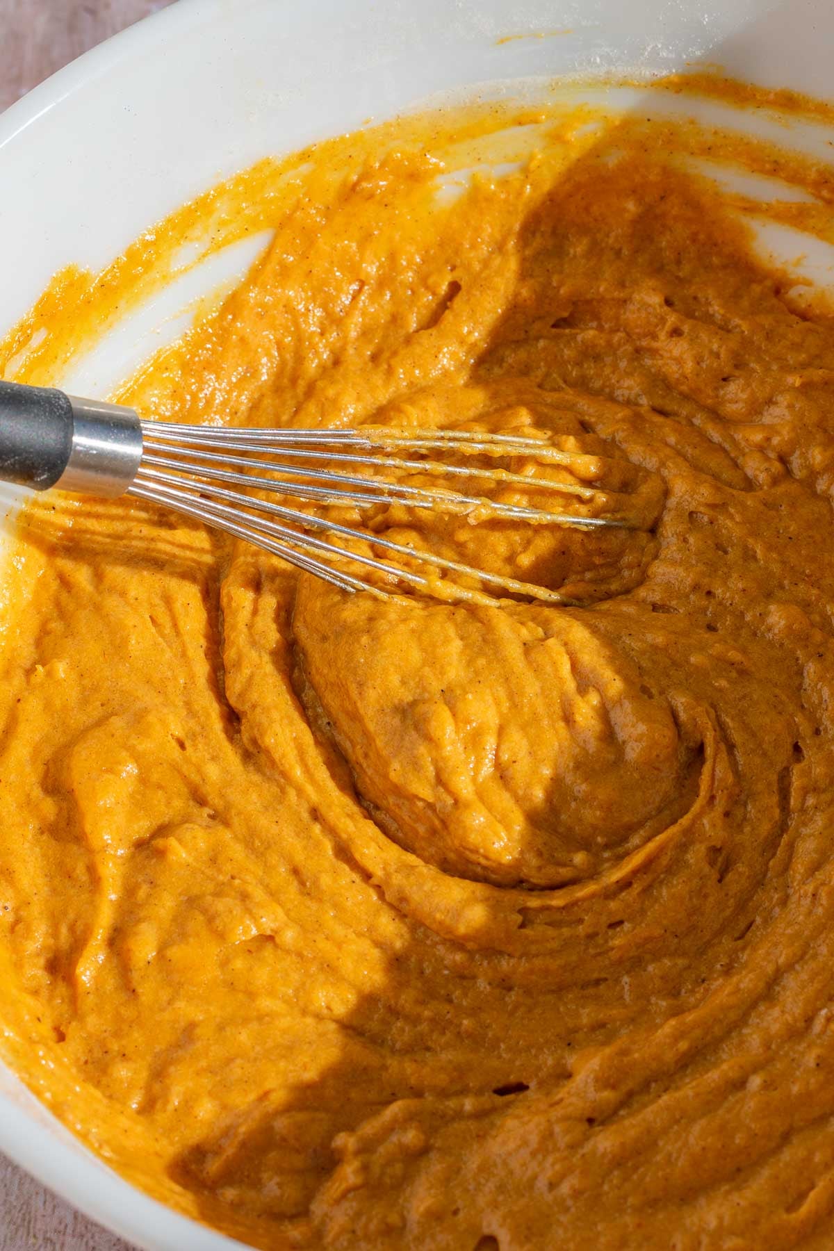 Whisked sourdough pumpkin bread batter in a bowl with a whisk.