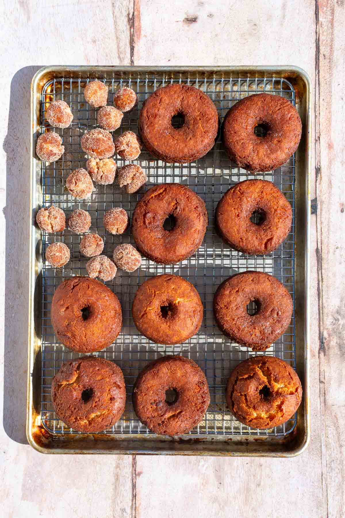 Fried sourdough apple cider donuts and donut holes on a wire rack.