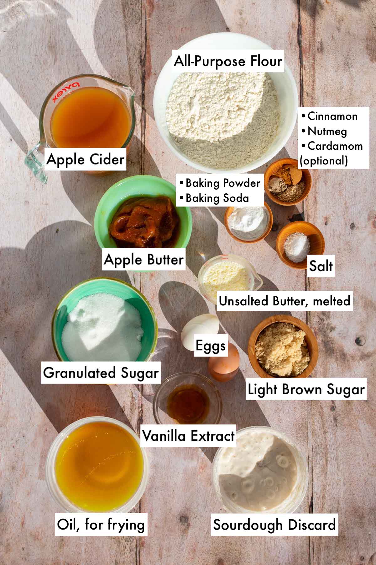 Labeled ingredients needed for sourdough apple cider donuts in bowls.