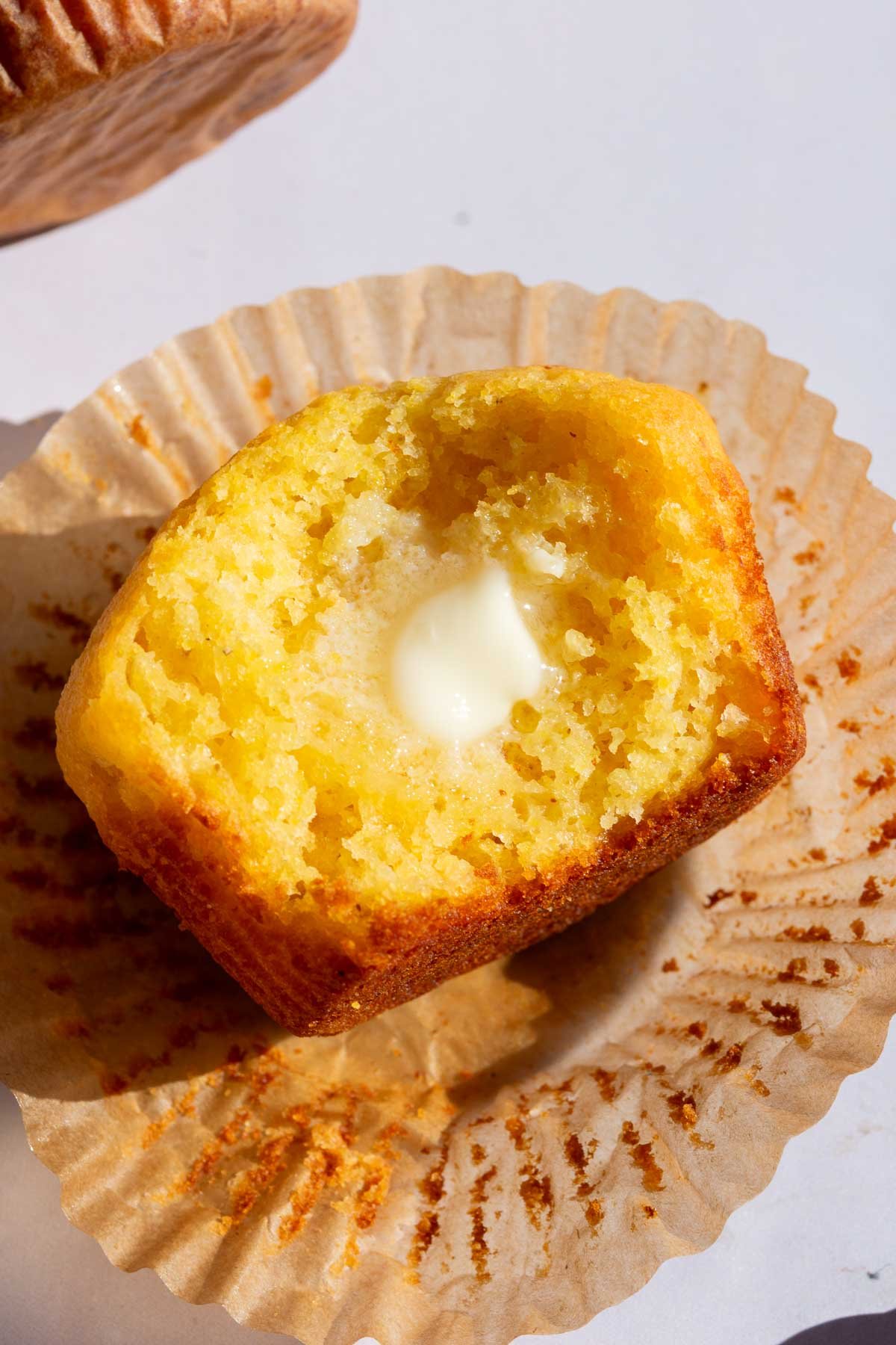 Melting butter on a sourdough corn muffin with a bite taken out of it.