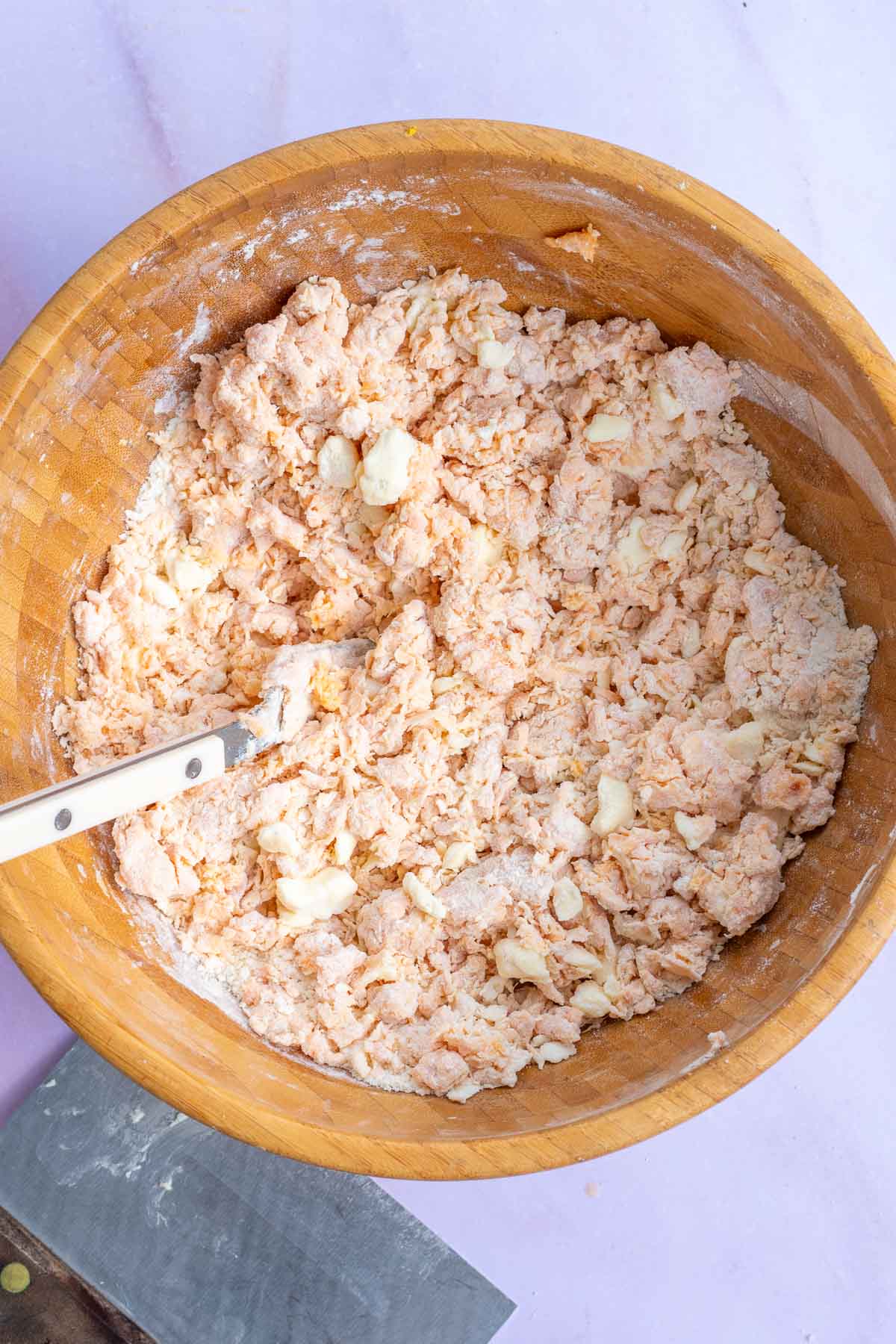 Large bowl of mixed dry and wet ingredients for sourdough sweet potato biscuits with a fork.