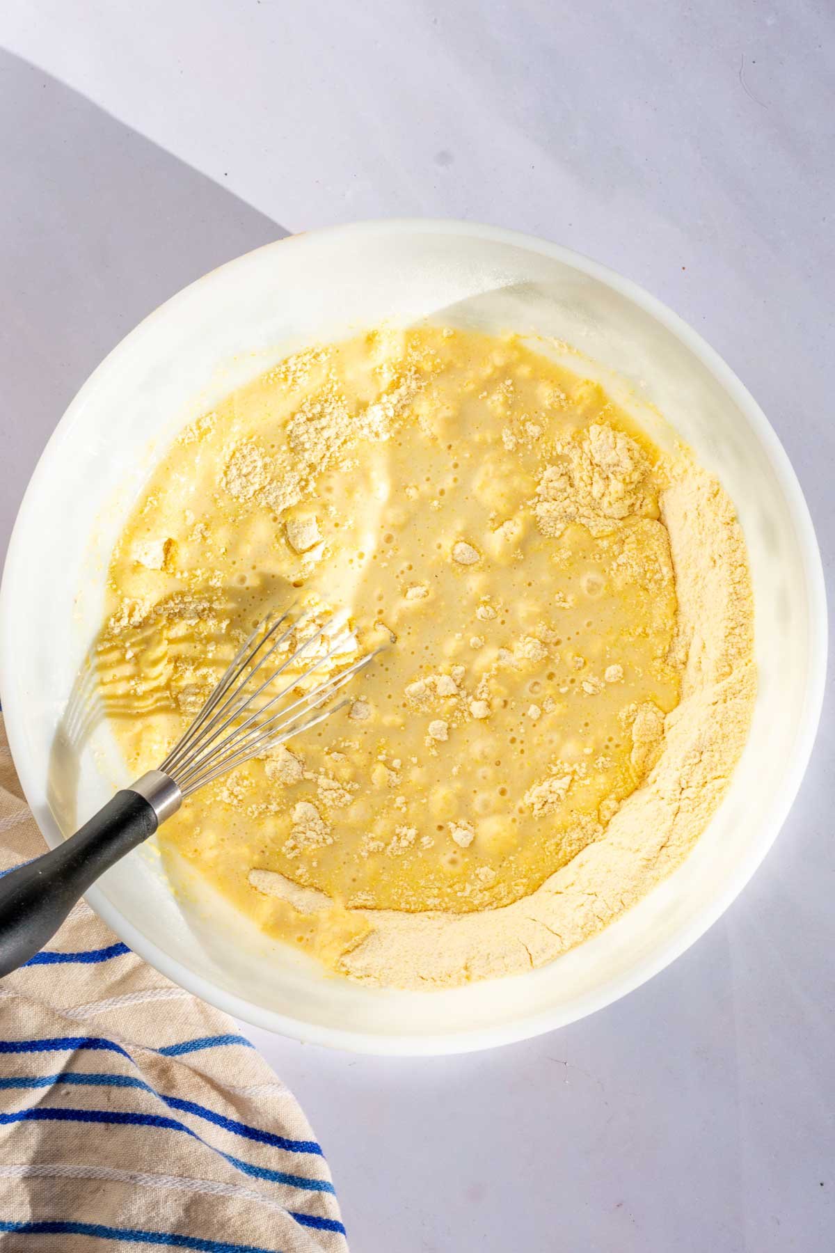 Mixing bowl of sourdough corn muffins batter with a whisk.