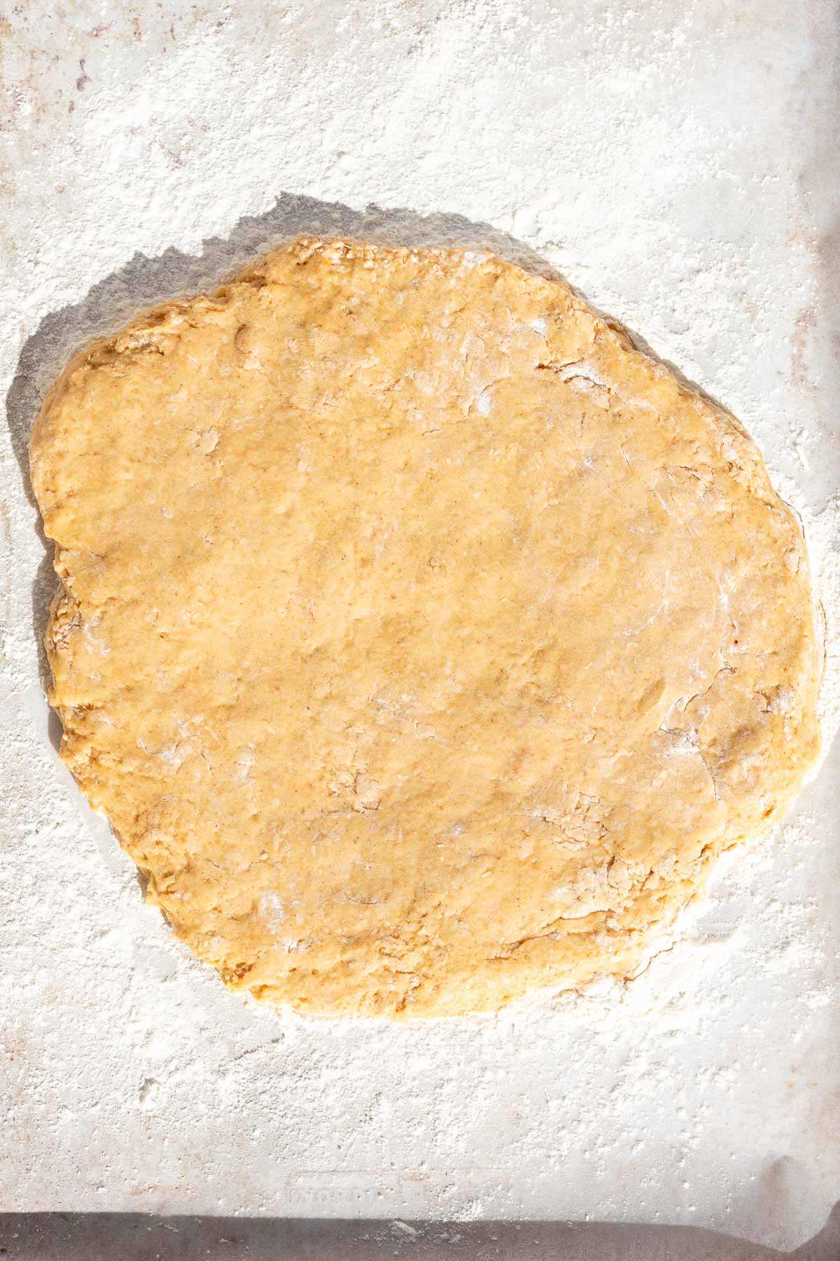 Sourdough apple cider donut batter patted into a round on floured parchment paper.