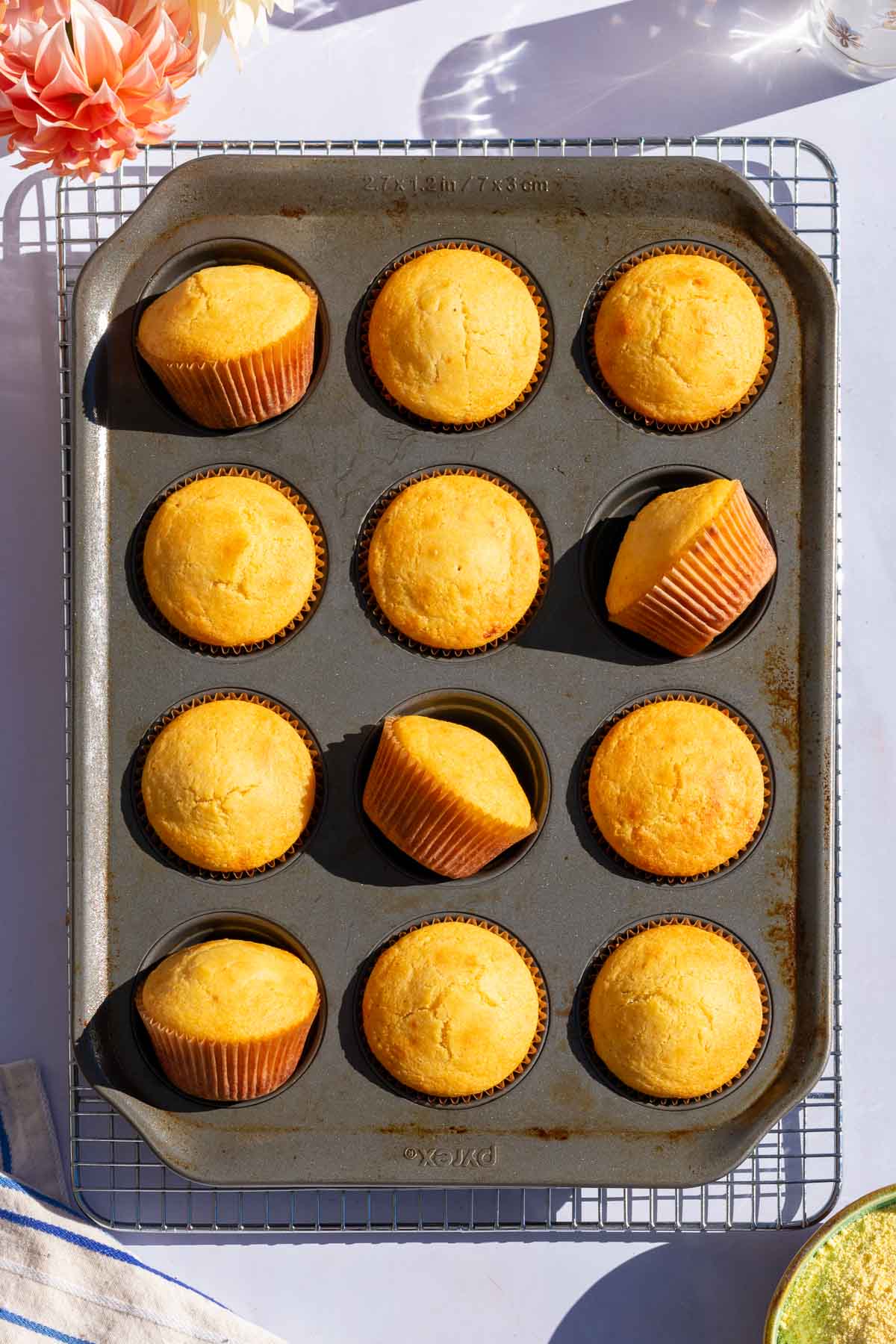 Twelve baked sourdough corn muffins in a muffin pan.