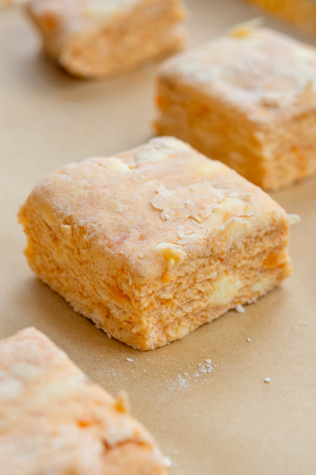 Close up of the flaky layers of a sourdough sweet potato biscuit before baking on a pan with parchment paper.