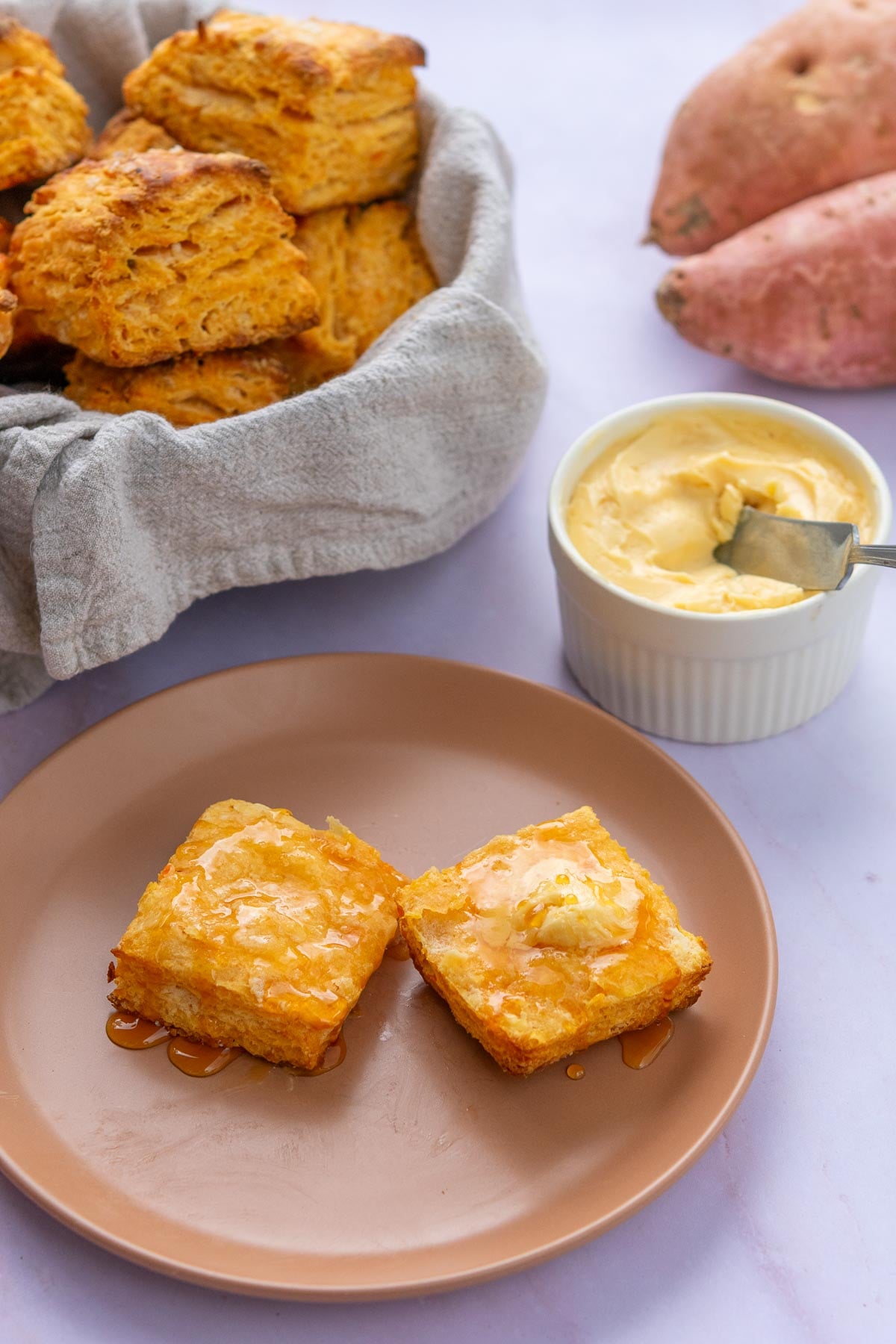 Split sourdough sweet potato biscuit with hot honey butter on a plate.