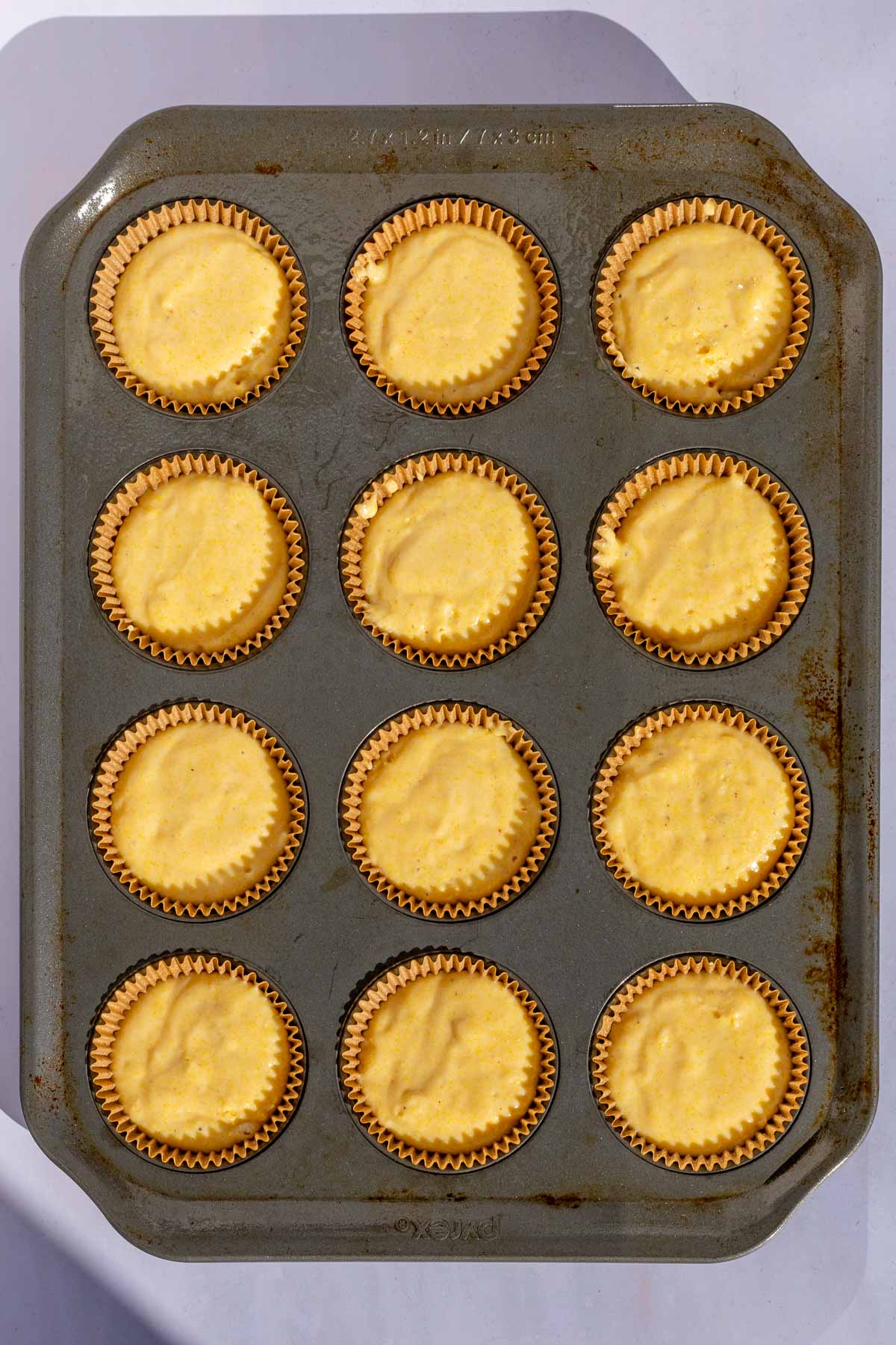 Muffin pan with twelve unbaked sourdough corn muffins.