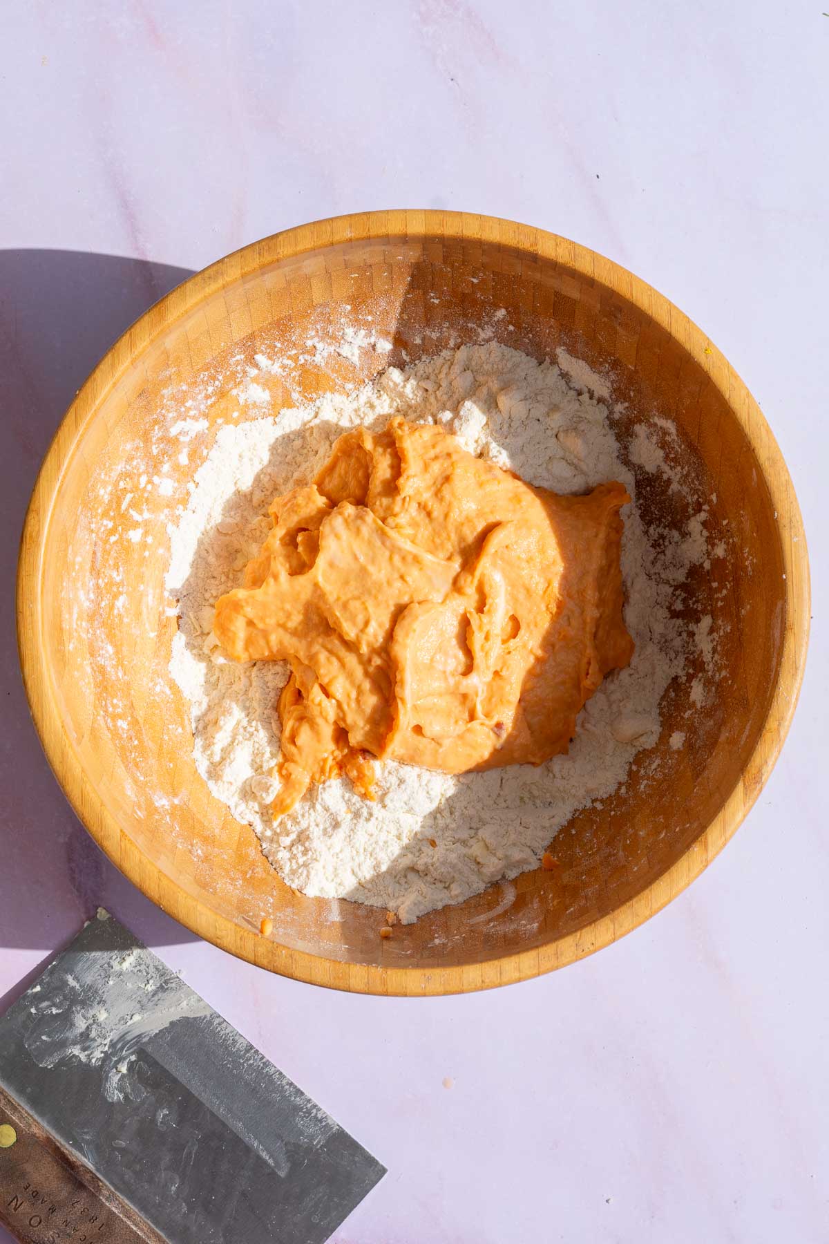 Wet ingredients including mashed sweet potatoes poured into bowl of dry ingredients. 