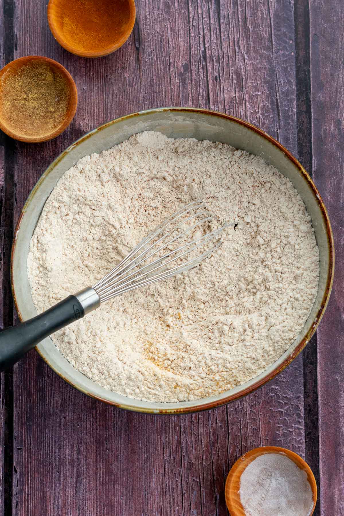 Bowl of dry ingredients for gingerbread cake mixed together with a whisk.