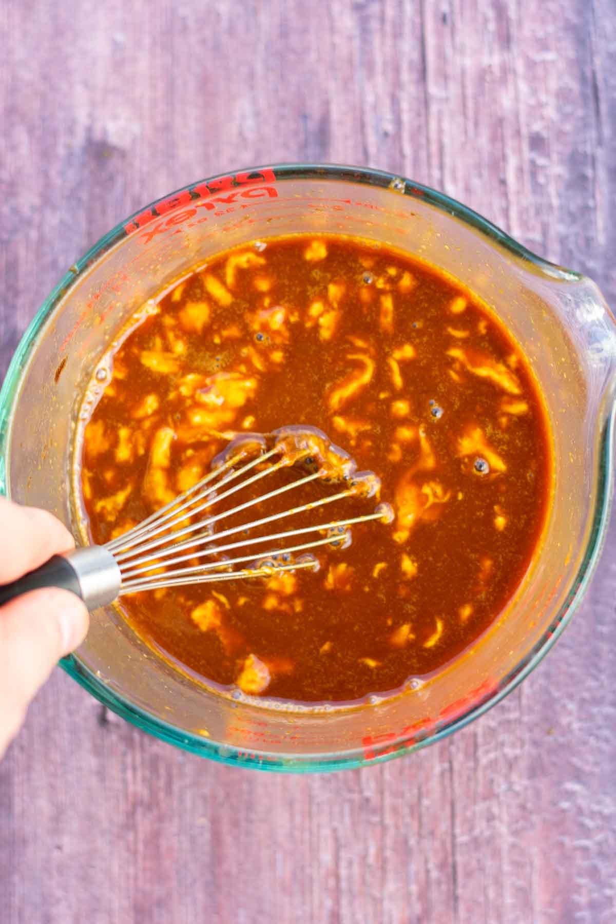 Molasses, sourdough discard, and hot water mixed together in a large liquid measuring cup with a whisk.