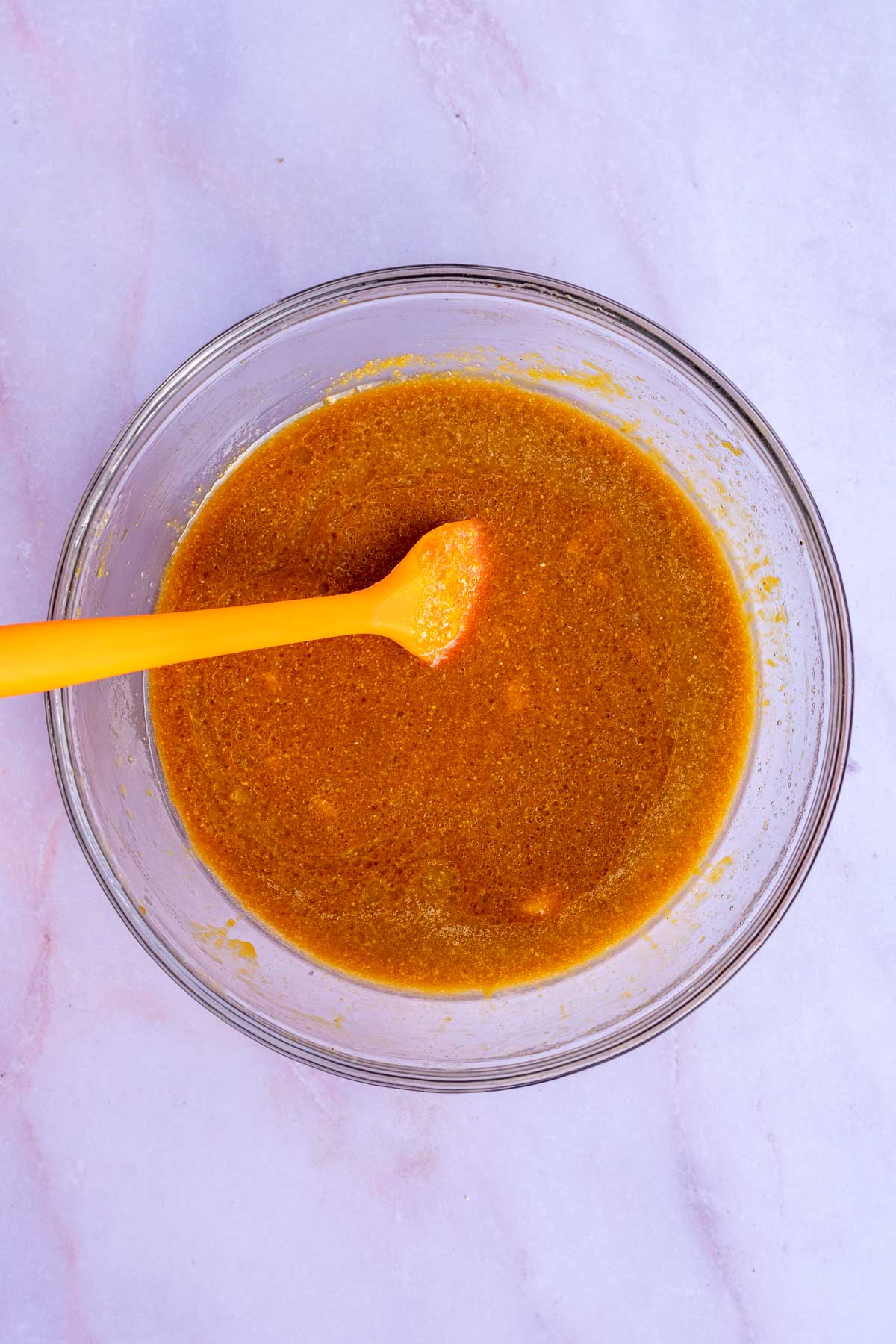 Molasses and melted butter added to bowl of cornmeal porridge with a spatula.