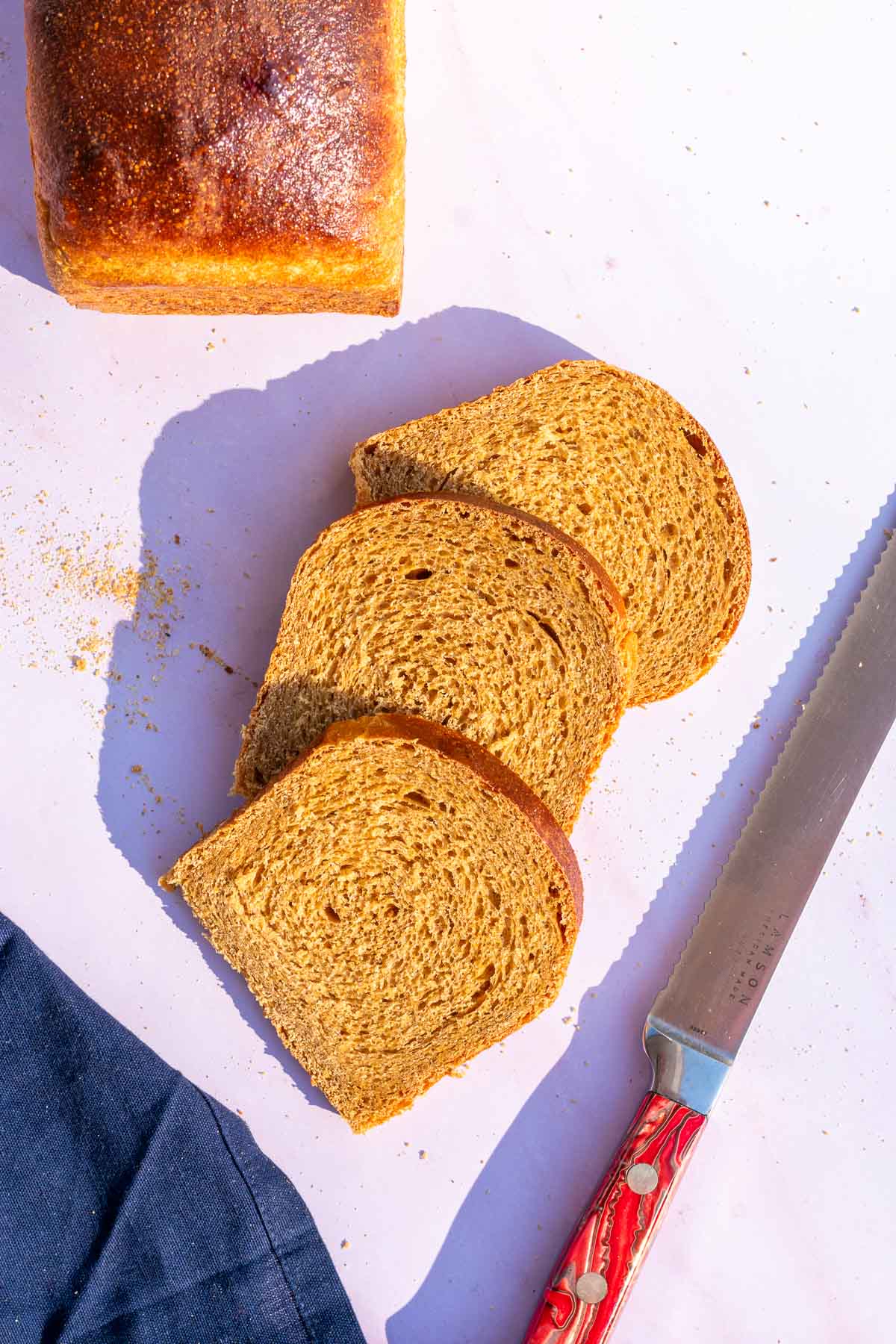 Slices of sourdough anadama bread with a bread knife.