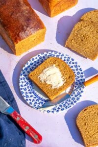 Slices of sourdough anadama bread on a plate with butter.