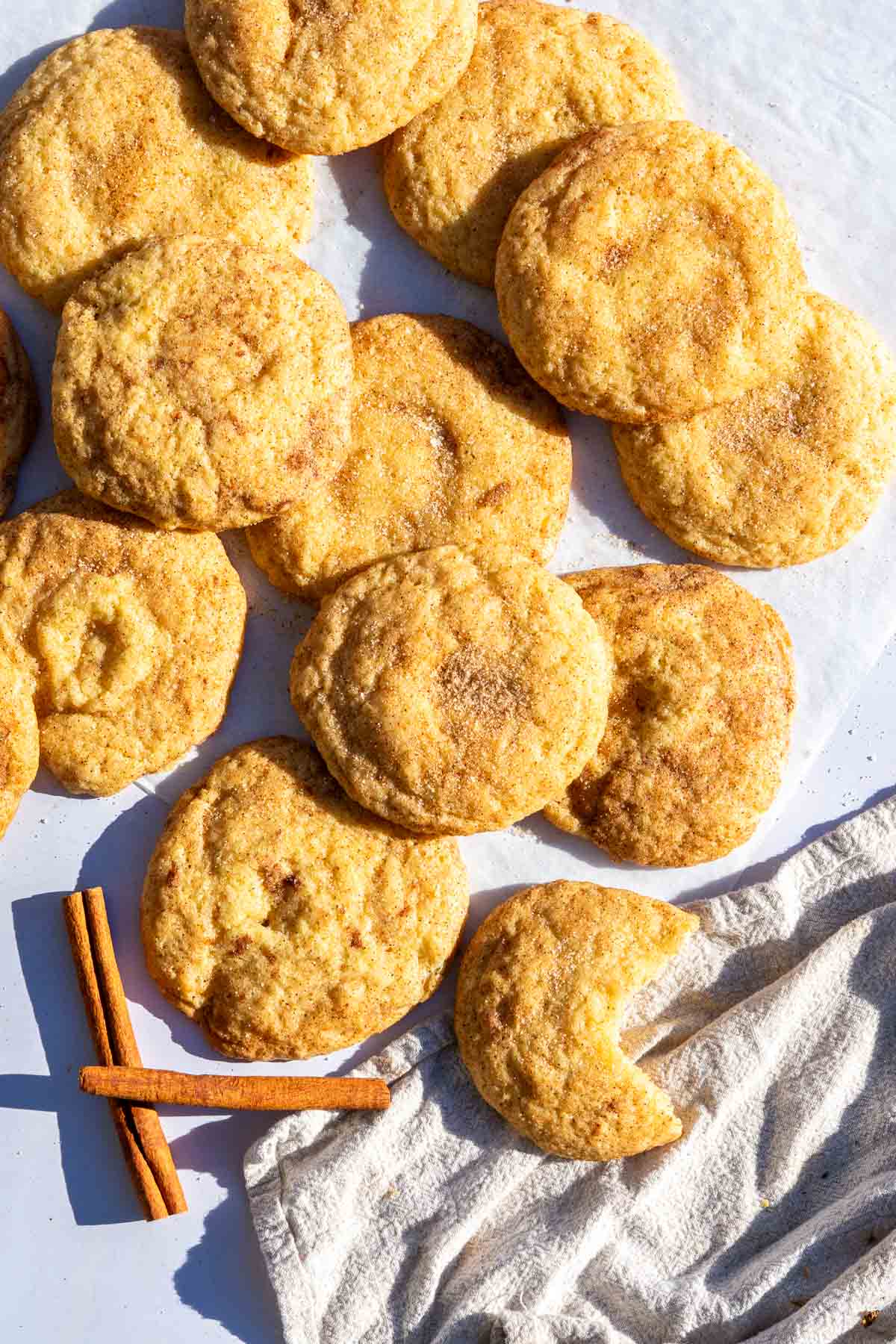 Many sourdough snickerdoodle cookies with a couple of cinnamon sticks.