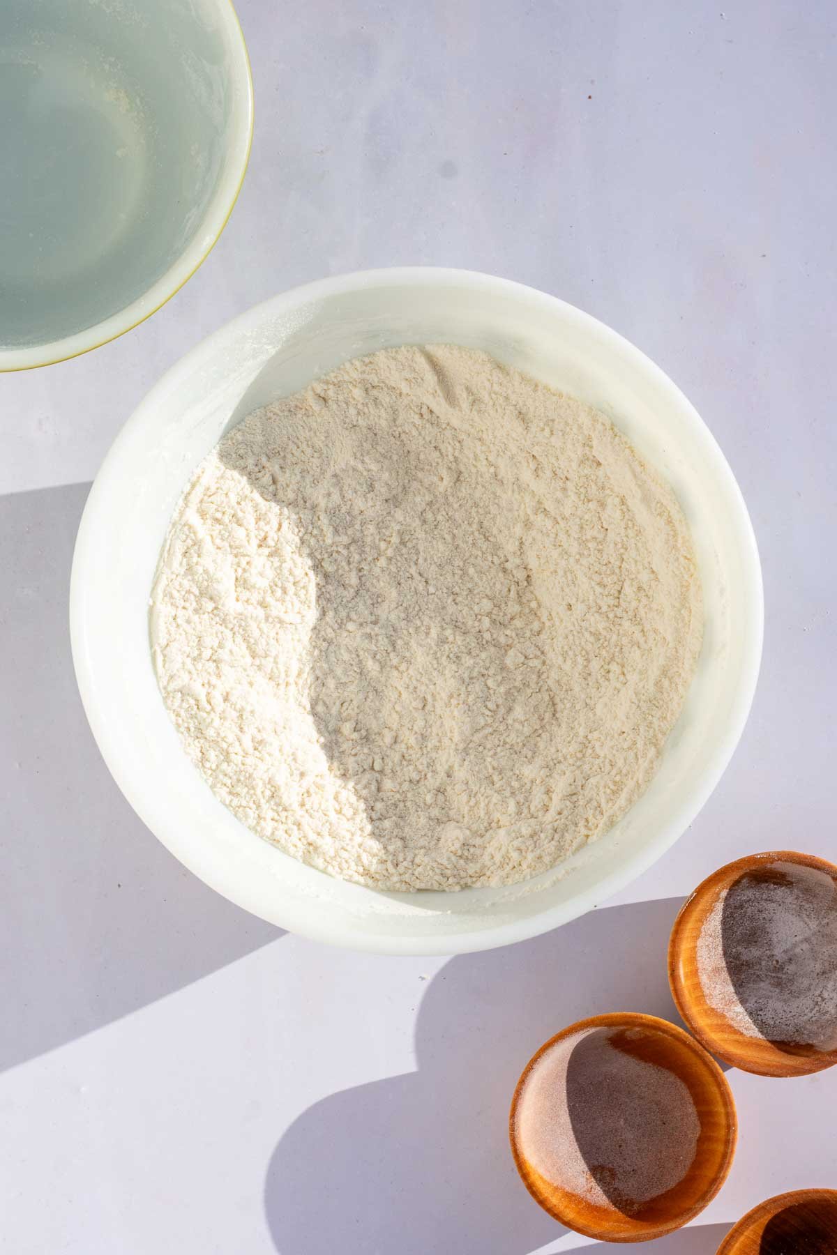 Bowl of mixed dry ingredients for sourdough snickerdoodle cookies with pinch bowls to the side.