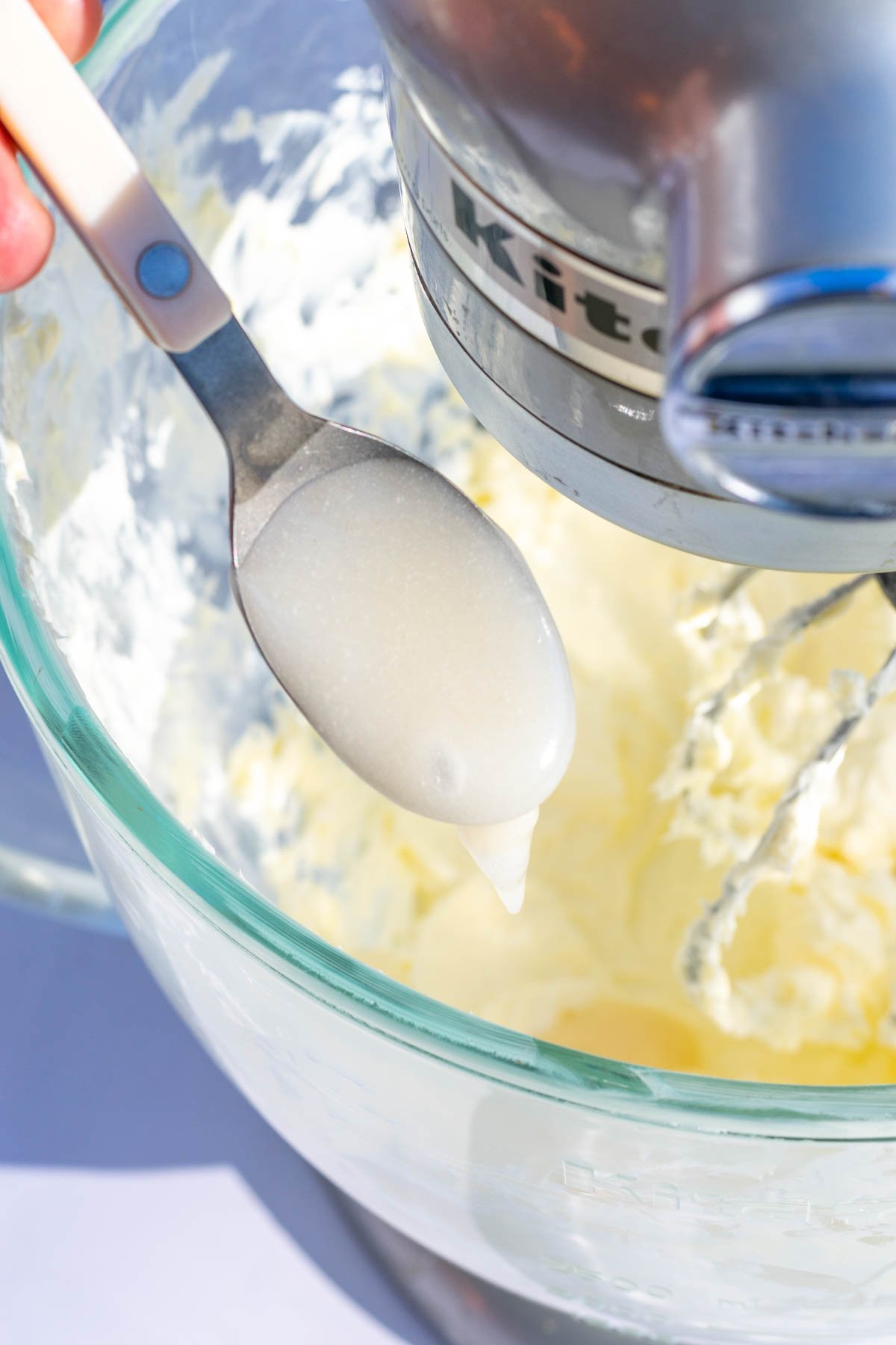 Spooning roux into bowl of stand mixer with whipped butter.