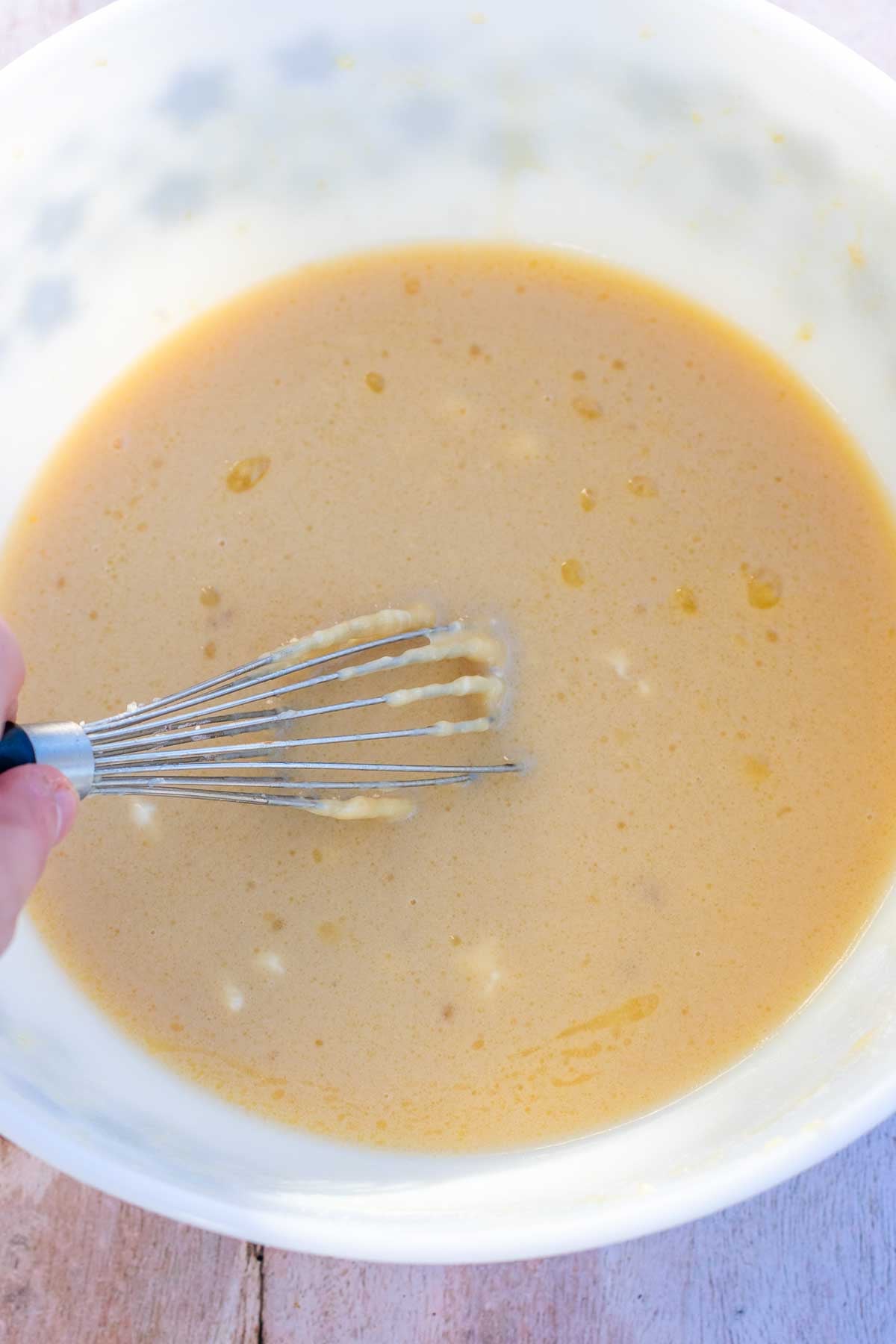 Bowl of mixed wet ingredients for sourdough chocolate peppermint whoopie pies with a whisk.