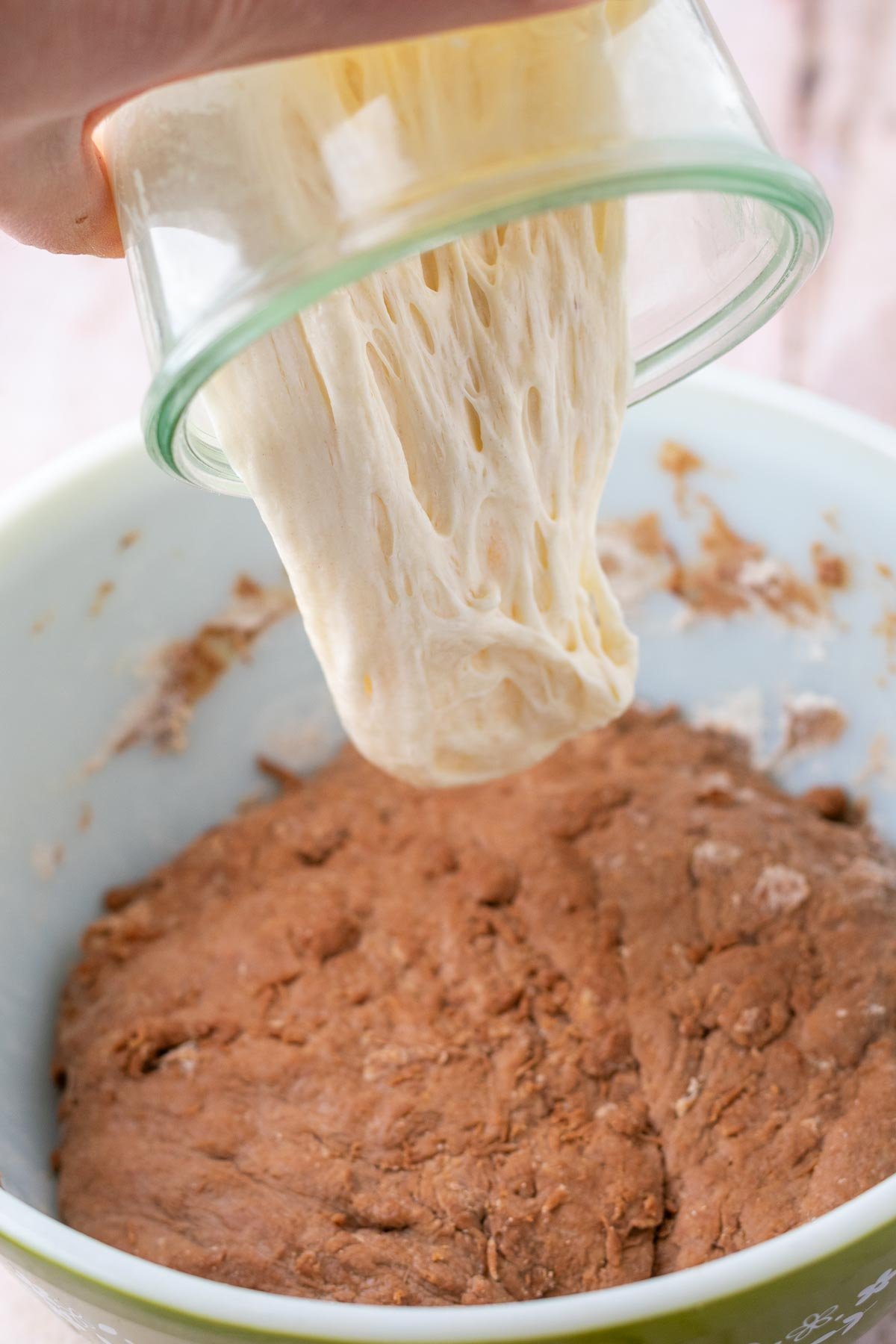Pouring jar of levain or sourdough starter into bowl of chocolate coffee sourdough bread.